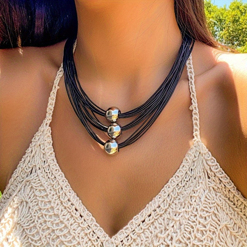 Bayramlar uchun ko‘p qatlamli dizayni va metallik sferik aksessuarlar bilan qora bejirimli taqinchoq