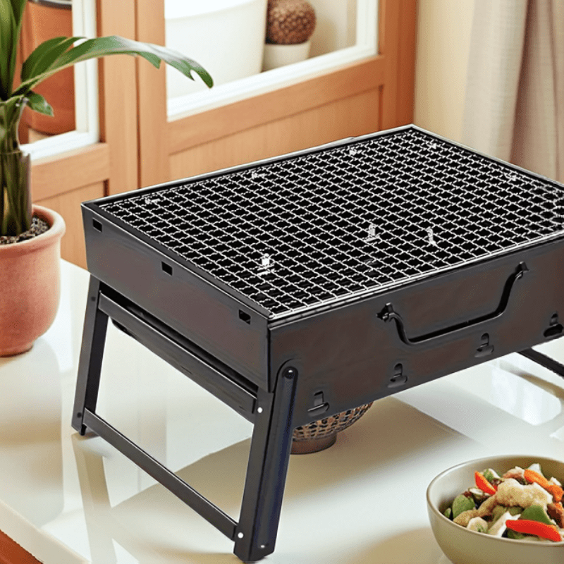 Parrilla portátil plegable de acero inoxidable, perfecta para acampar, hacer picnic y cocinar al aire libre. Diseño compacto y duradero.