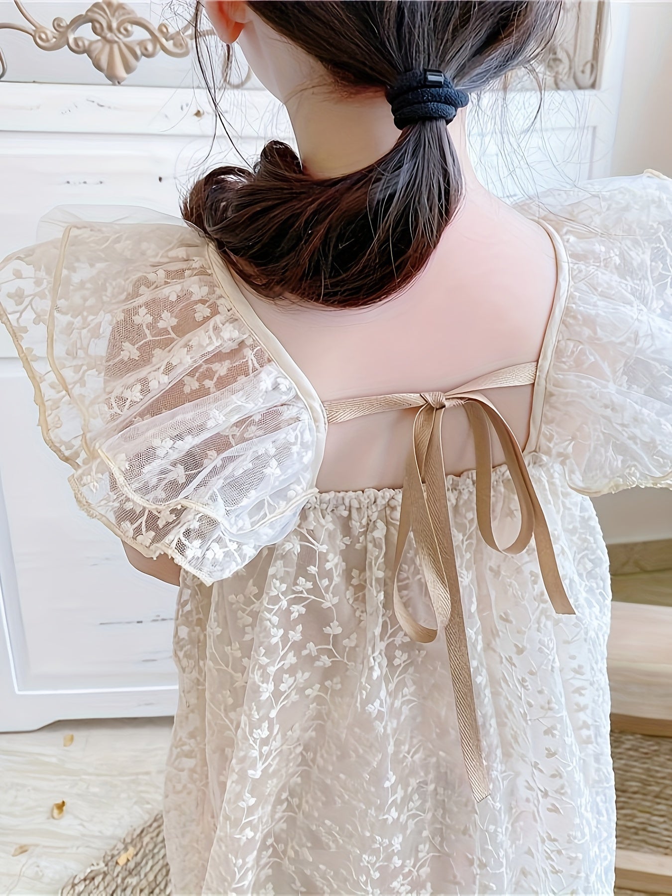 Qizlar uchun gullar bilan jacquard, uchuvchi yenglar va orqa qismi ochiq dizaynga ega nafis dantel ko'ylak.