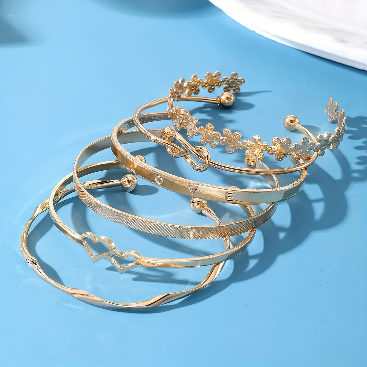 6 ta zamonaviy bilaguzuklar to'plami, gullar, tugunlar va yurak dizaynlariga ega. Ularni kundalik kiyimlaringiz yoki bayram kiyimlaringiz bilan birlashtiring. Ushbu sozlanadigan zargarlik buyumlari har qanday ko'rinishni bezatish uchun mukammaldir.