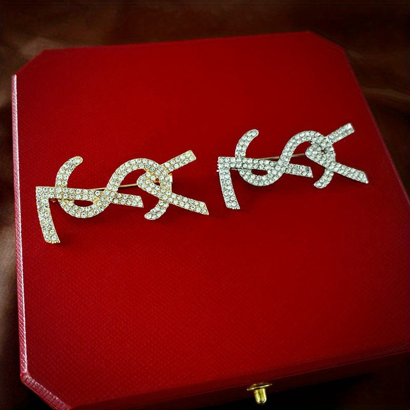 Bu zamonaviy va nafis French ilhomlangan harf broshining ajoyib olmoslar bilan bezatilgan, ayollar uchun o'z kiyimlariga elegans va hashamat qo'shishni istaganlar uchun mukammal. Zamonaviy va yuqori darajadagi jozibani oshirish uchun ideal.