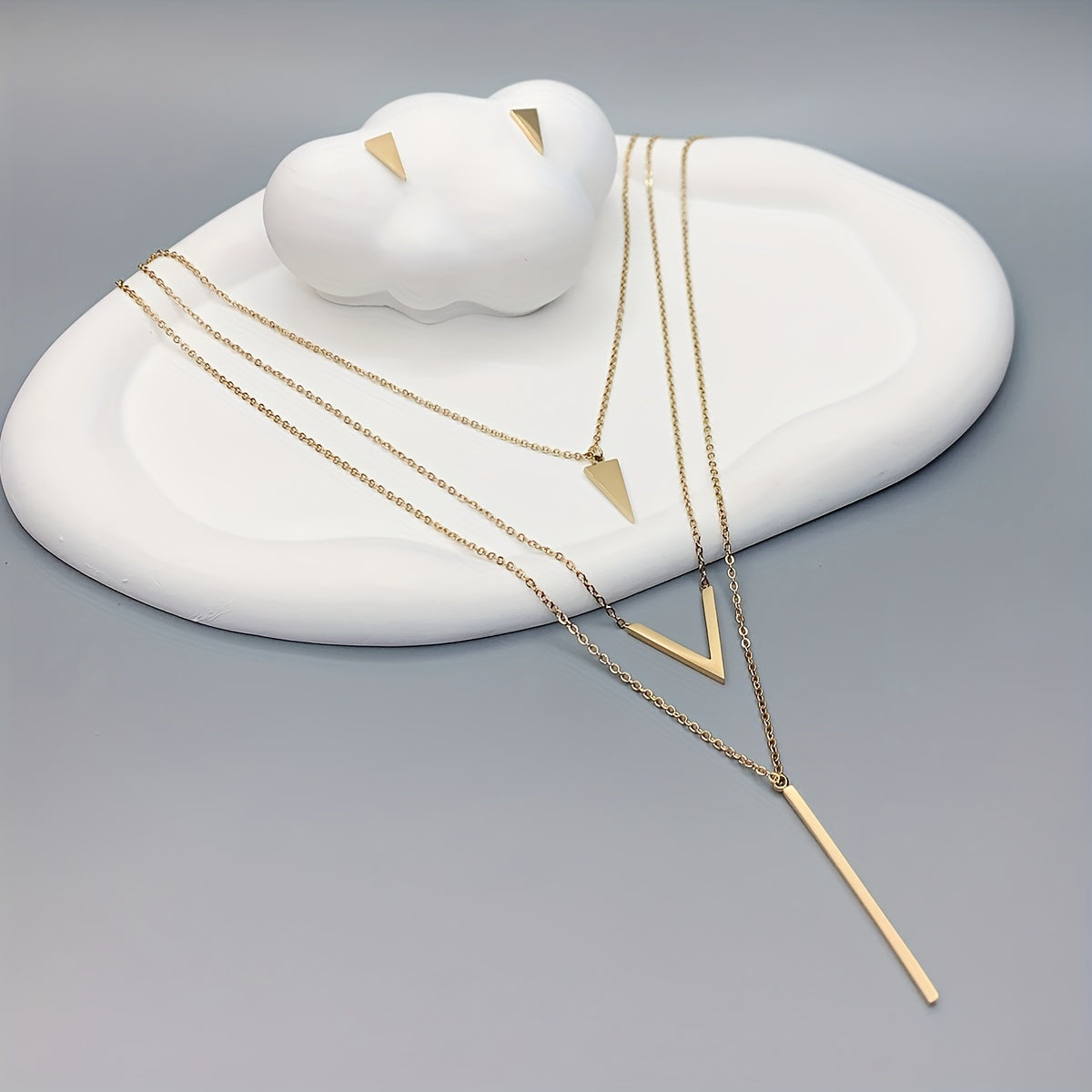 Uch dona zanglamas po'latdan yasalgan uzun tasma V-shaklidagi geometrik pendant, ko'p qatlamli marjon va uchburchakli sirg'alar bilan. Tug'ilgan kun yoki bayram sovg'asi, kiyim bezaklari yoki partiya aksessuarlar sifatida mukammal.