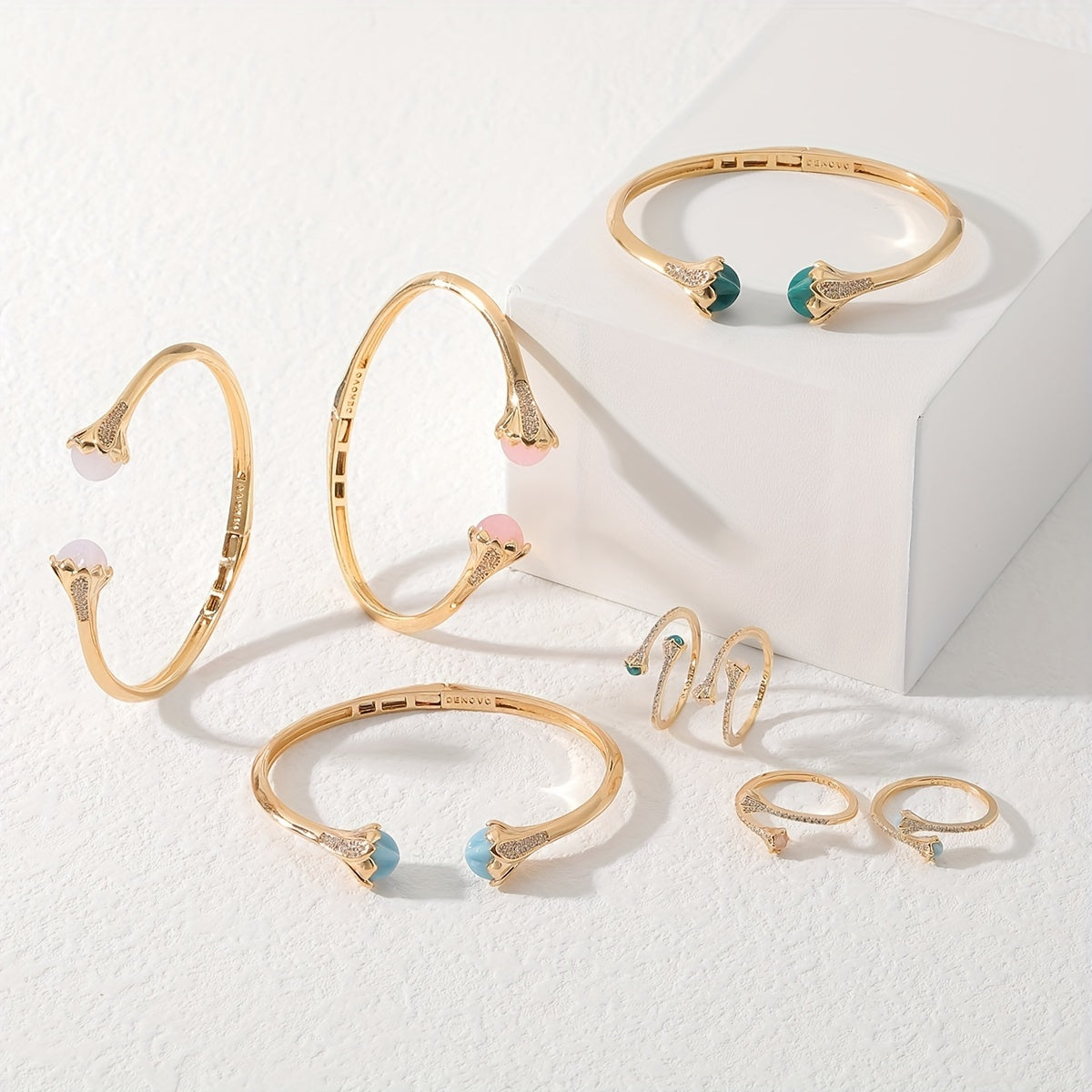 Ayollar uchun nafis va minimalistik zargarlik to'plami - 18K oltin qoplamali mis, zirkoniya va rangli rezina aksessuarlar bilan - Moslashuvchan ochiq bilaguzuk va mos keluvchi uzukni o'z ichiga oladi - Kundalik kiyish yoki maxsus tadbirlar uchun mukammal