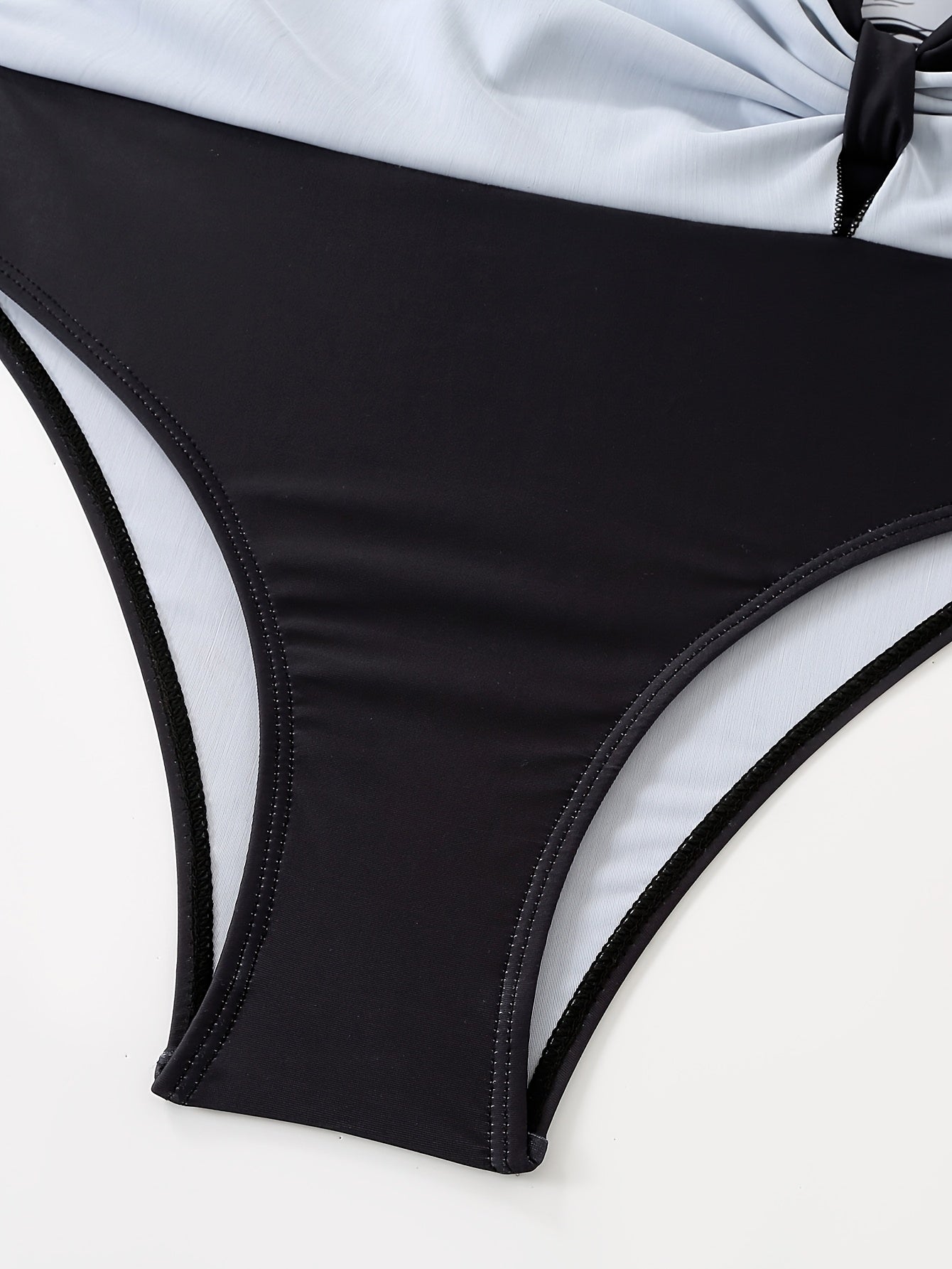 Gul naqshli suzish kiyimi, yubka shaklidagi pastki qismi, qora va oq rangda ingichka yuqori bel dizayni, cho'ziluvchan polyester/elastan aralashmasi, olib tashlanadigan yostiqlar, plyaj va basseyn uchun mukammal.