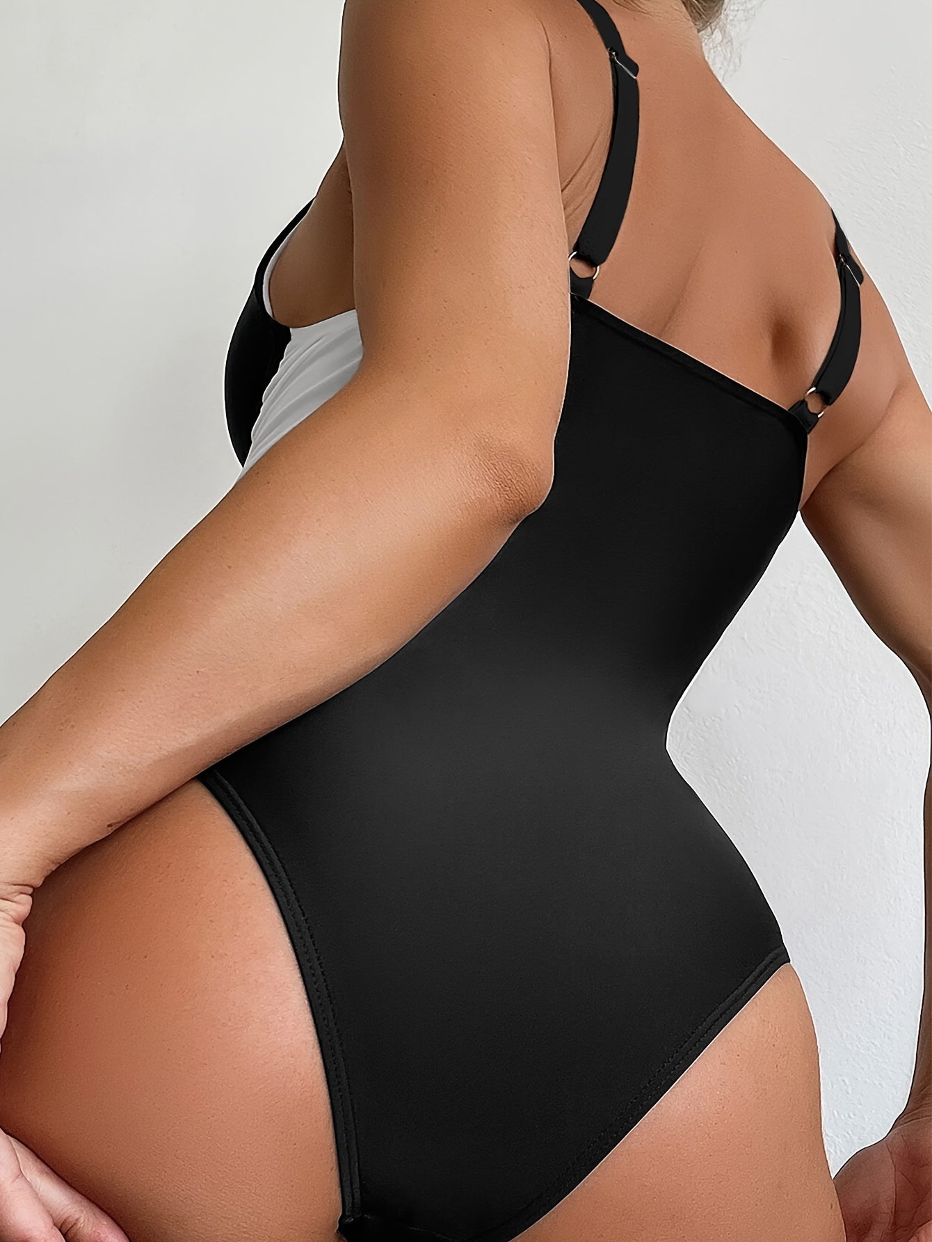 "Savdo" Ushbu ayollar uchun qora va oq rangdagi, yumaloq bo'yinli bir parcha suzish kiyimi, ingichka va belni shakllantiruvchi xususiyatlarga ega.