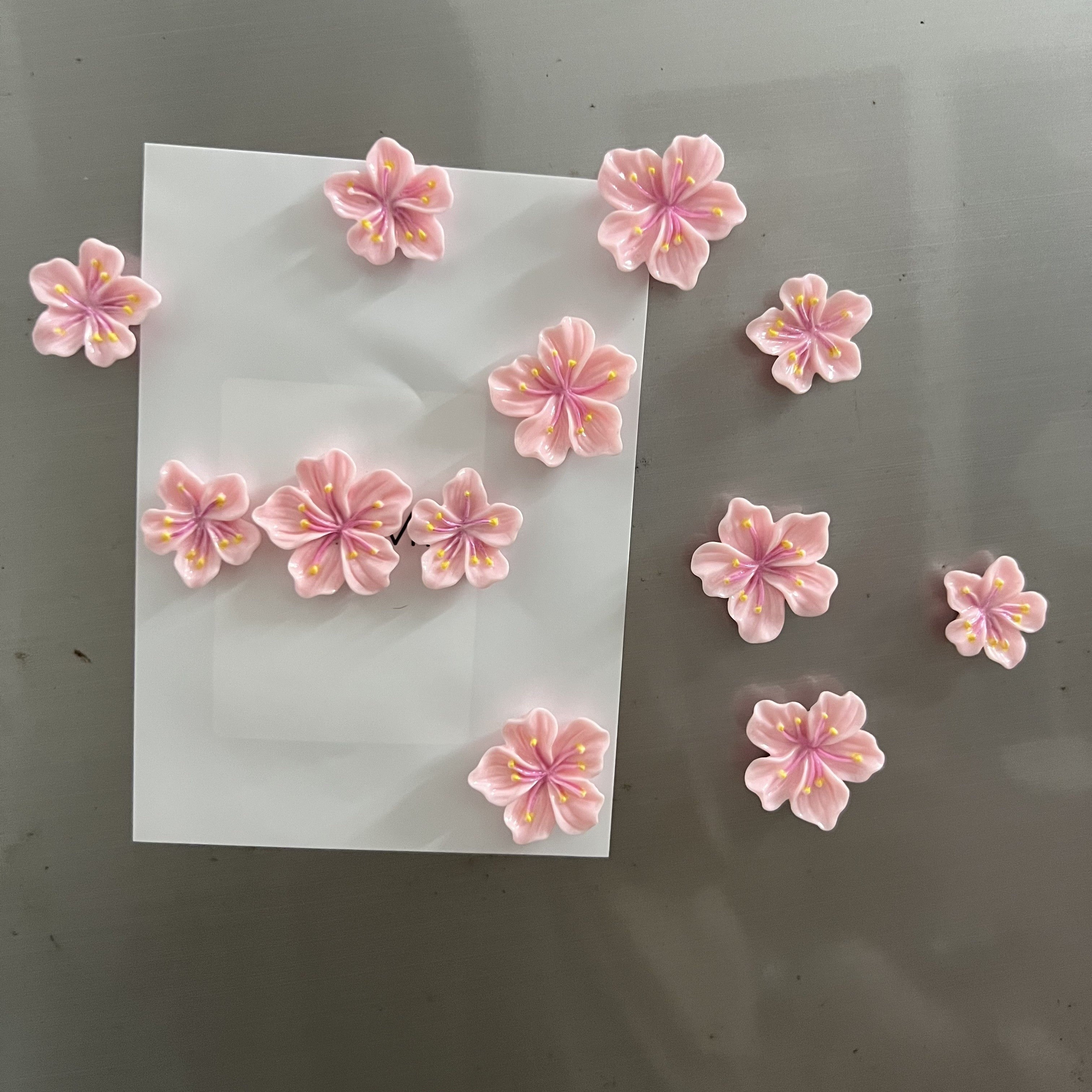 Oshxonangiz yoki ofisingizga jozibadorlik qo'shing bu yoqimli 12-burchakli Pink Cherry Blossom Refrigerator Magnet Set bilan. Mustahkam ABS materialidan tayyorlangan, bu chiroyli va bezakli magnitlar ofisning oq taxtalarida, oshxona shkaflarida va