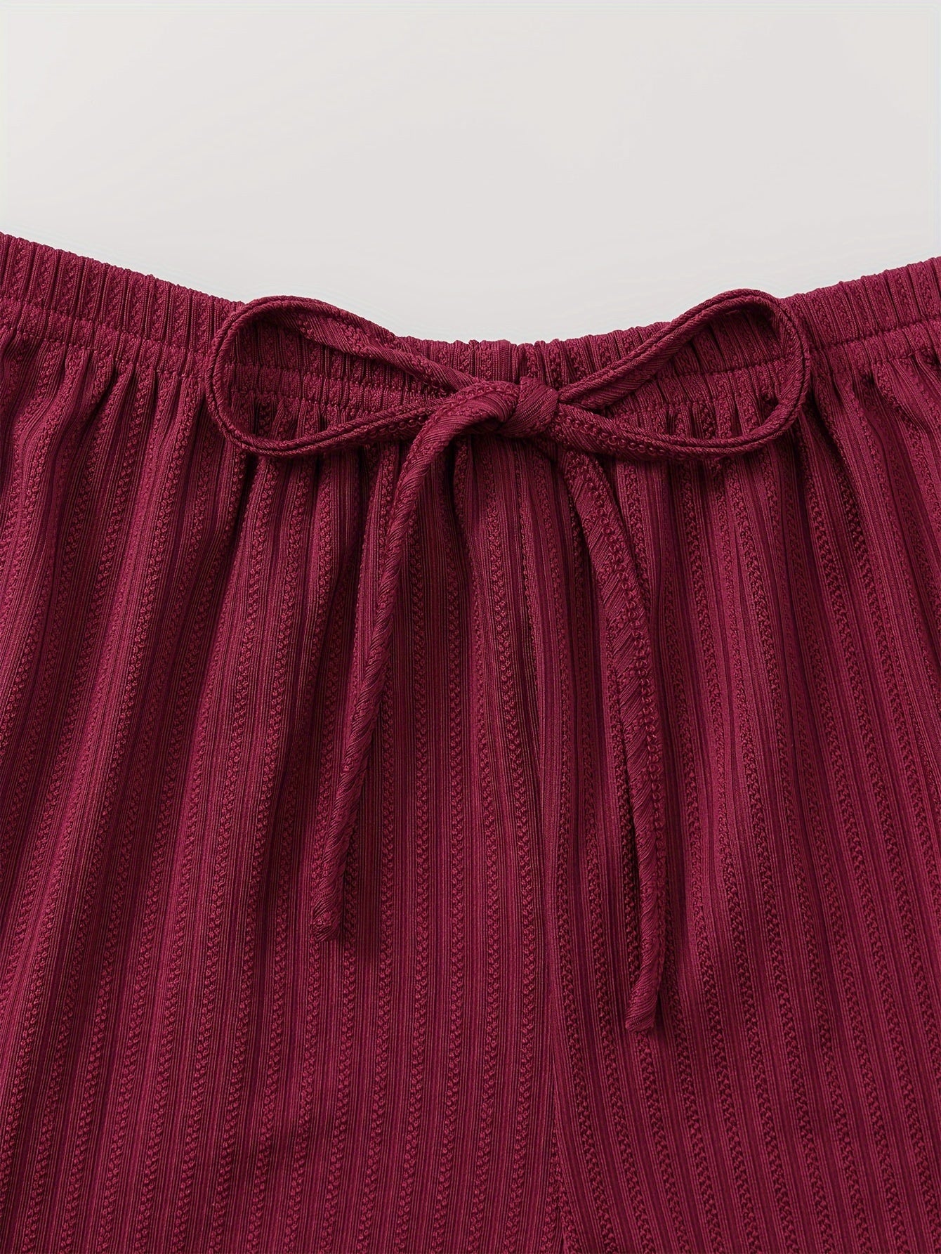 Ayollar uchun dantel bilan bezatilgan ribbed pijama to'plami, V-shaklidagi kamzuli yuqori va tortma belli shortlar bilan. Mashinada yuvish mumkin. Bir nechta ranglarda mavjud.