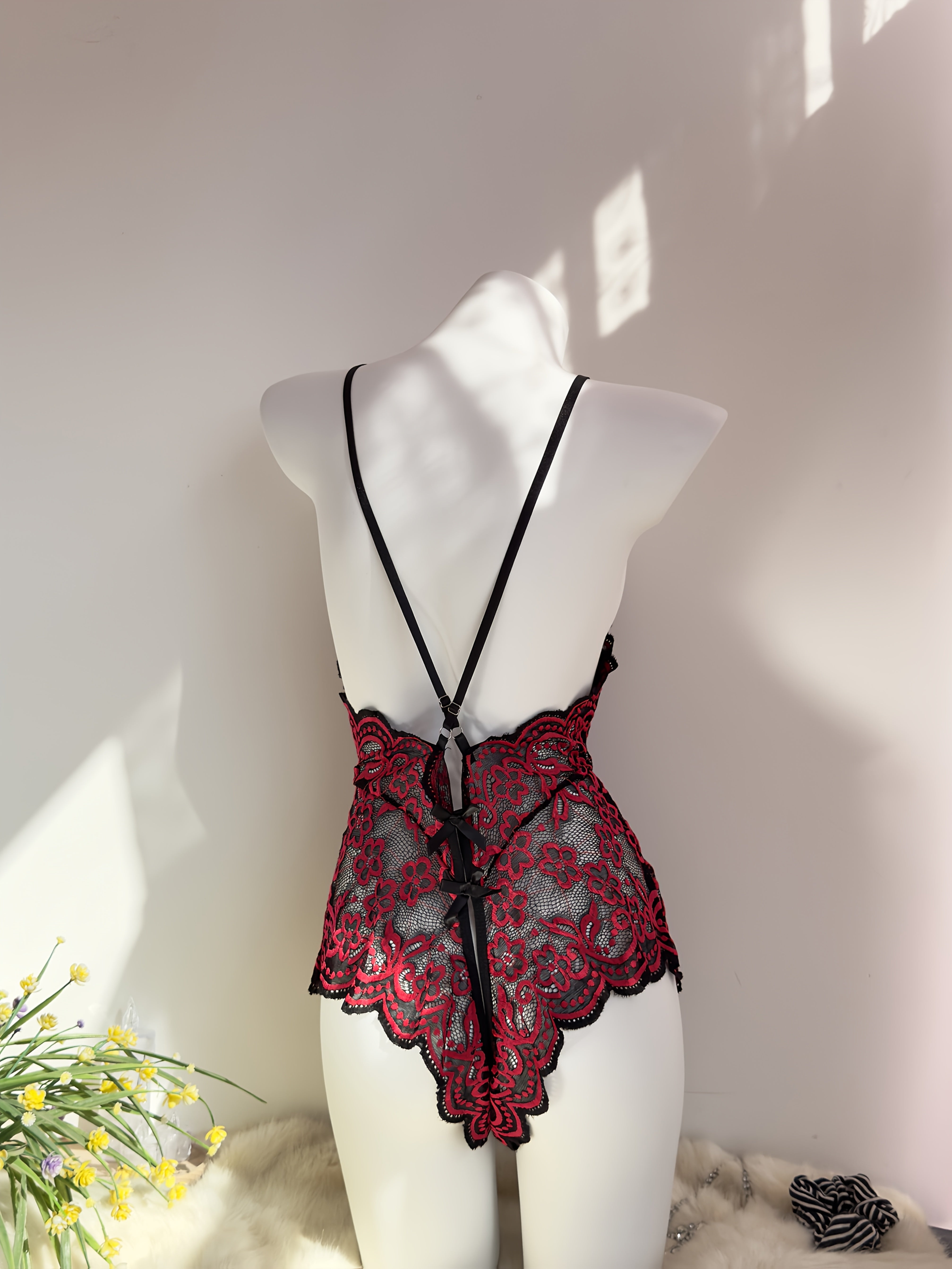 Jozibali dantel bodysuit, chuqur V-shakl, ochiq orqa va kesish tasma dizayni bilan.