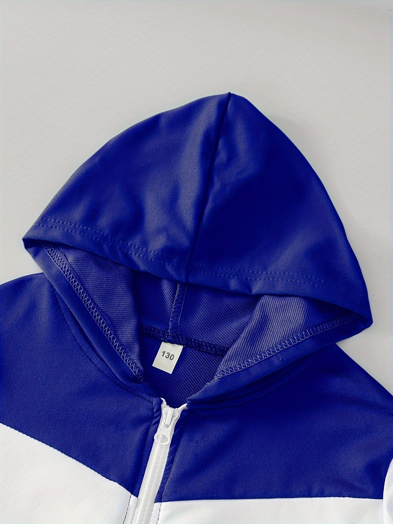 Elastik cho'ziluvchan polyester to'qilgan pullover, rangli blok dizayni bilan. O'g'il bolalar uchun keng fit, bahor/kovak fasllarida ochiq havoda faoliyatlar uchun mukammal. Mos keluvchi shimlar to'plami bilan birga keladi.