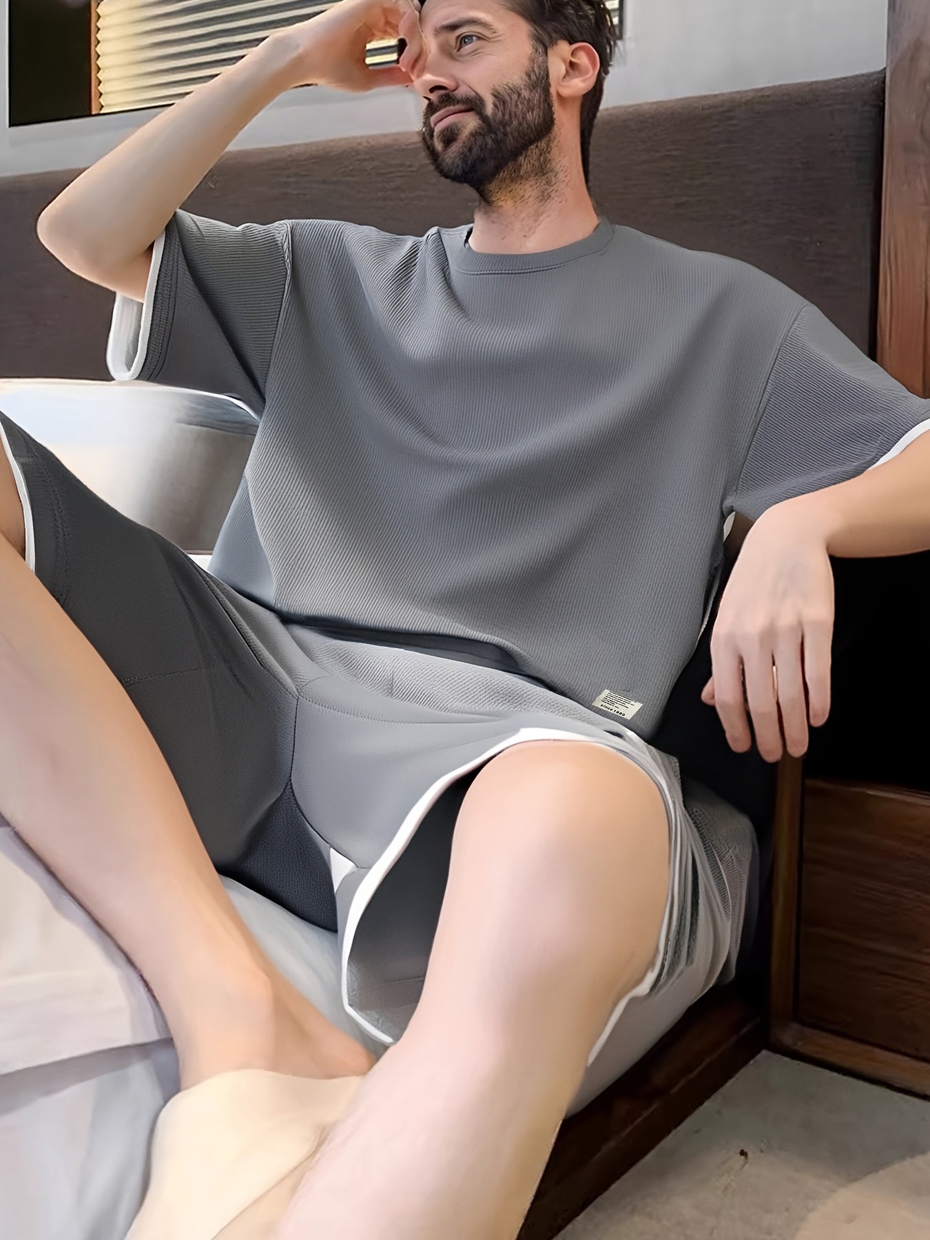 Erkaklar uchun tasodifiy vafli to'qilgan pijama to'plami, kulrang va qora rangda, qisqa yengli yuqori va elastik belga ega shortlar. Quyi qismida aplikatsiya bezaklari va qulaylik uchun yumshoq polyester mato mavjud.