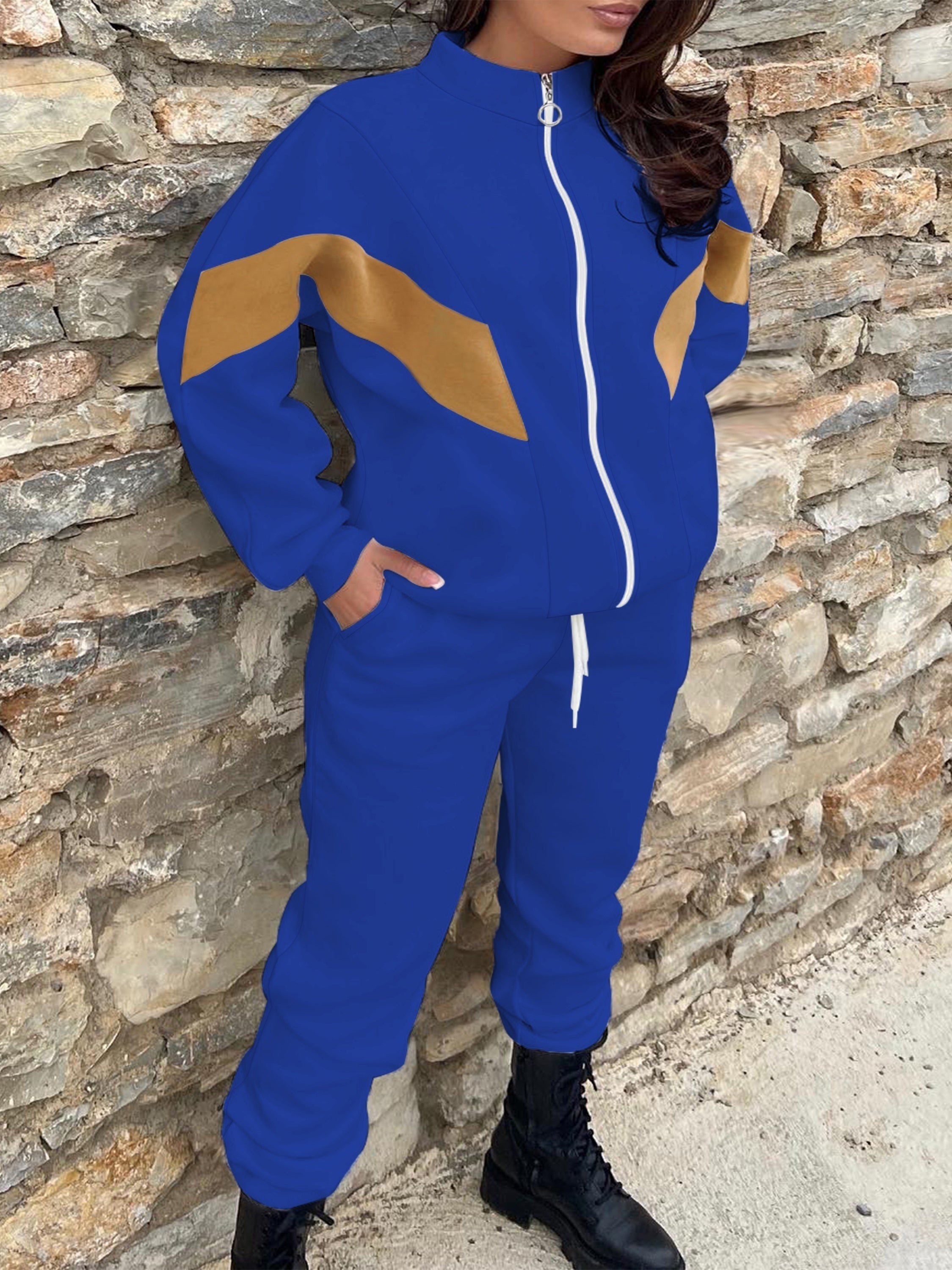 Ayollar uchun tasodifiy sport uslubidagi ikki qismli to'plam: cho'ziladigan cho'ntaklari va tortish qismiga ega ko'k va sariq fermuarli kurtka va mashinada yuvilishi mumkin bo'lgan polyester aralashmasidan tayyorlangan sport shimlar.