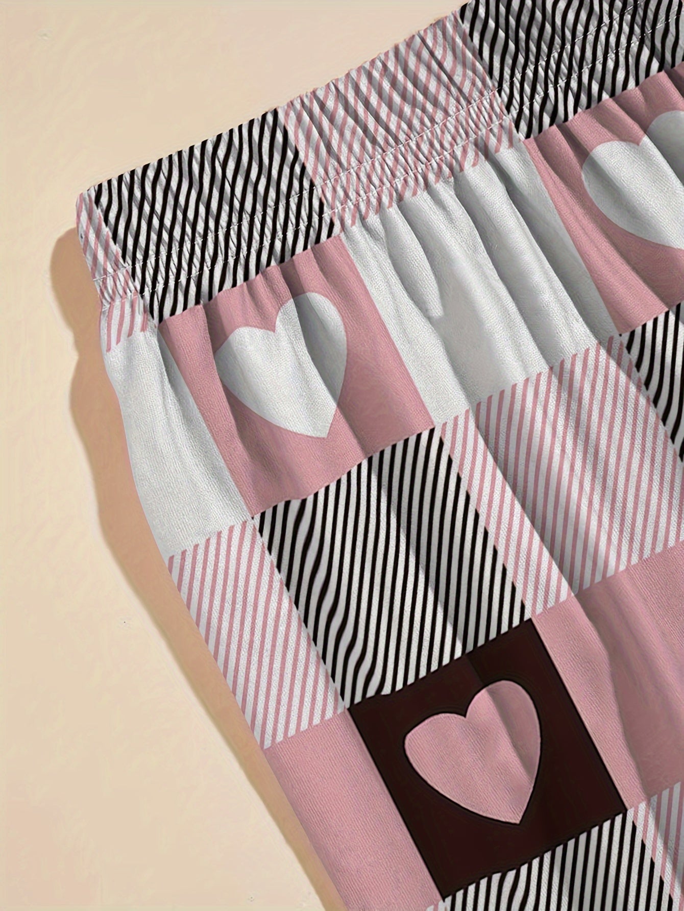 Ayollar uchun yurak grafikali futbolka va plaid shimlar to'plami, tasodifiy polyester to'qimadan tayyorlangan, qisqa yengli yuqori qismi va elastik belga ega dam olish shimlari. Dam olish yoki uyqu kiyimlari uchun mukammal.