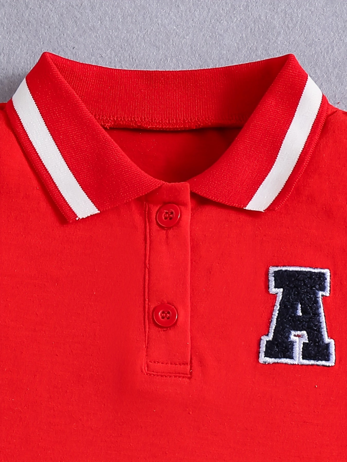 Qizlar uchun qizil tennis va sport libosi, nafas oladigan, teri so'radigan polyesterdan tayyorlangan, cho'ziluvchan va yengsiz dizayni bilan sport va tasodifiy kiyimlar uchun qora yozuvlar bilan sportiy nafislikni taqdim etadi.