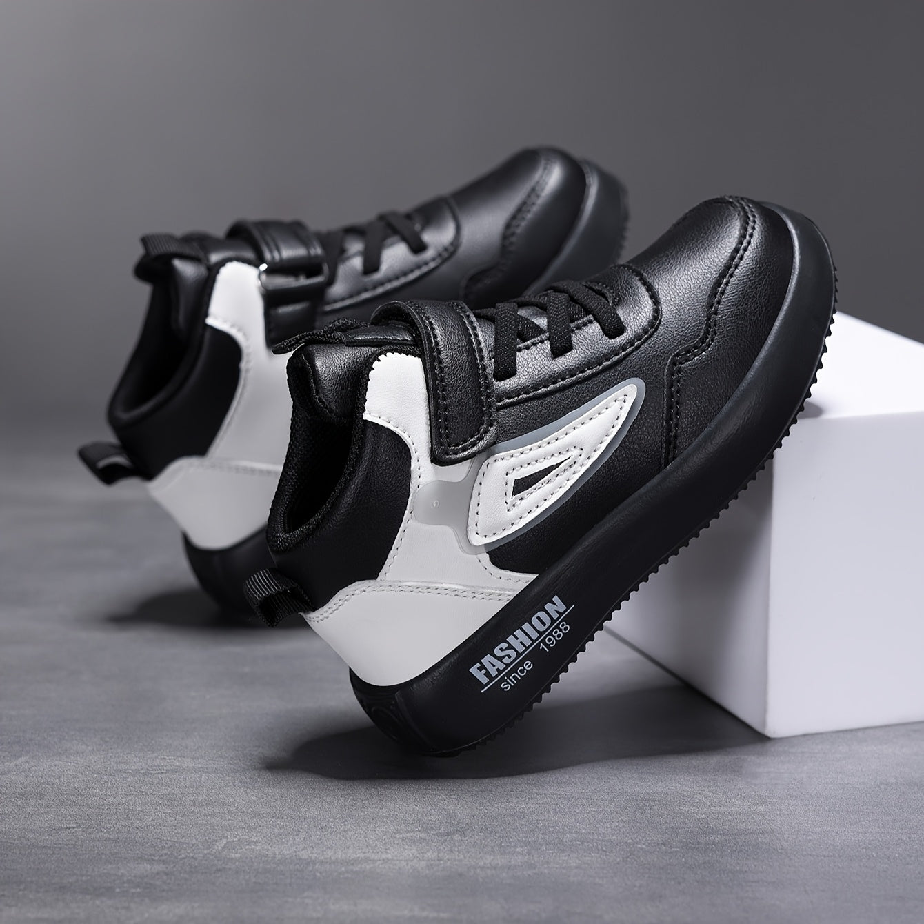 Bolalar uchun retro o'rtacha balandlikdagi krossovkalar qora va oq rangda, oson bog'lash mumkin, kundalik faoliyatlar va yugurish uchun mukammal.