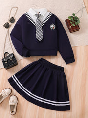 Yosh qizning kampus uslubidagi ikki qismli to'plami: Qisqa keng sviter ko'ylagi + bog'ichli chiziqli pliseli yubka.