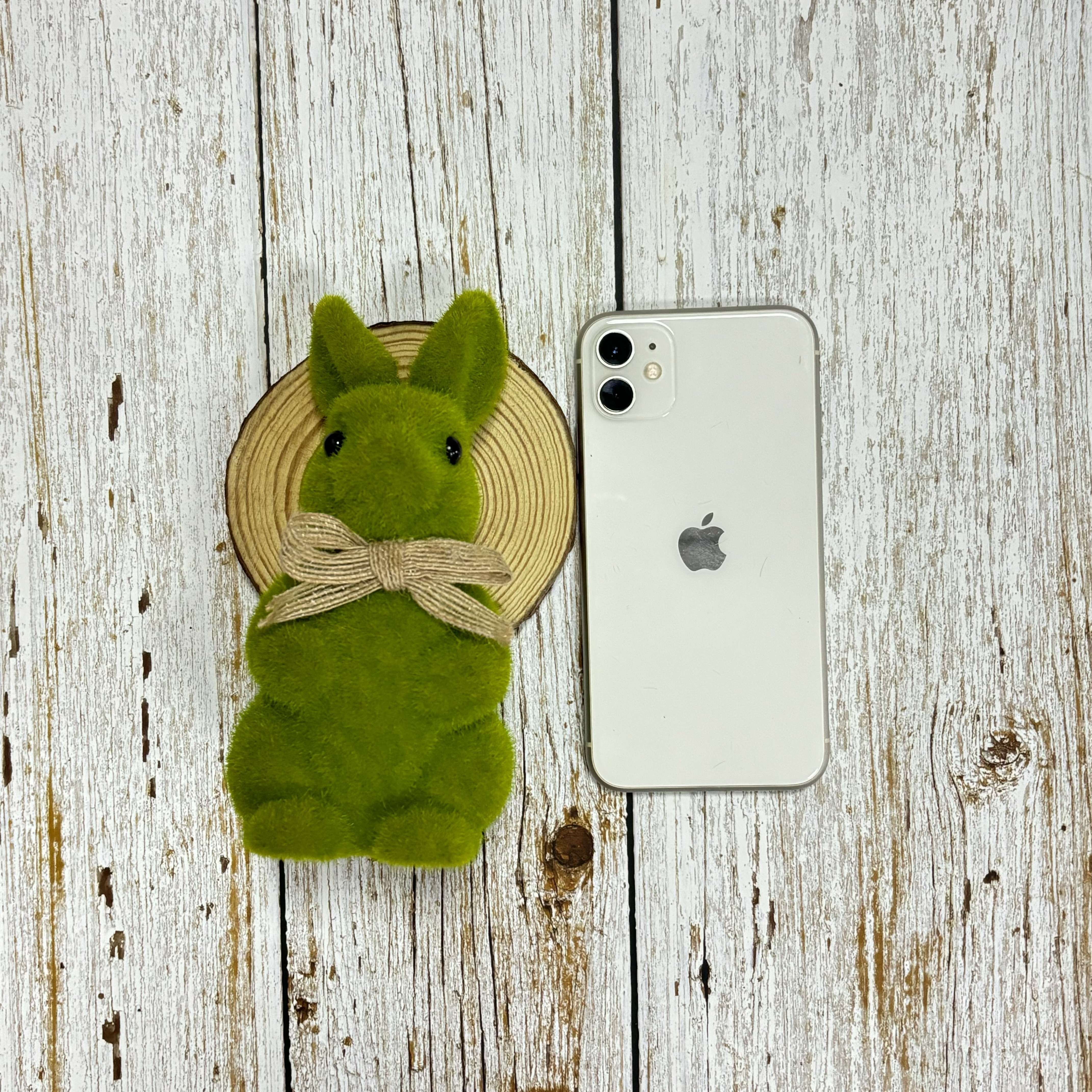 Charming 16.76 sm yashil to‘qilgan quyon haykali, Pasxa va bahor bog‘i bezaklari uchun, lenta aksent bilan. Bayram tadbirlari va uy hovlisi ko‘rinishi uchun mukammal.