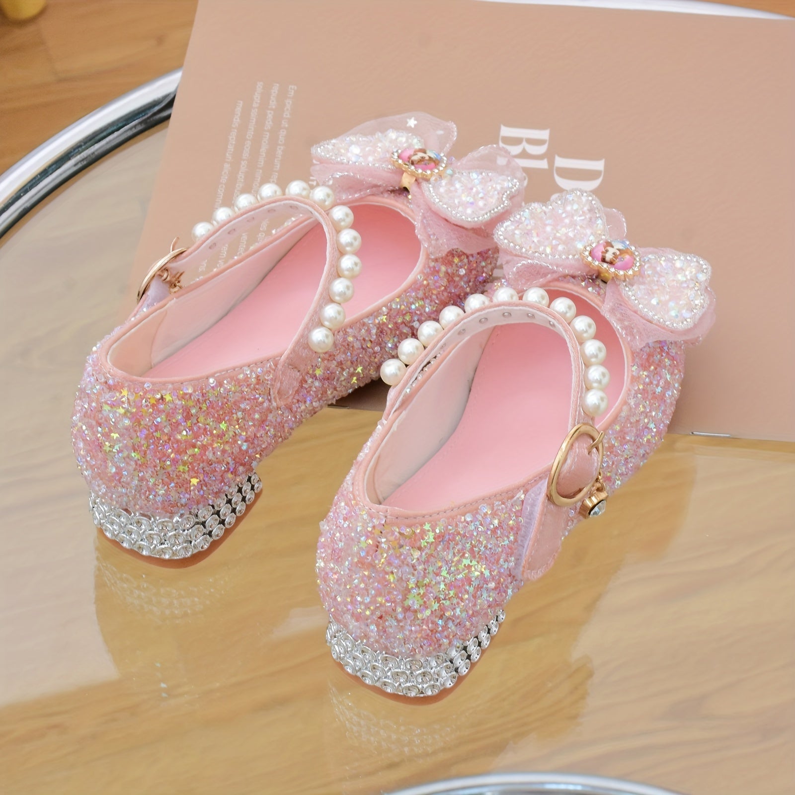 Pushti porloq kapalak kamonli Mary Jane tekis poyabzal, marvarid aksentlari bilan, to'ylar, partiyalar va rasmiy tadbirlar uchun mukammal.