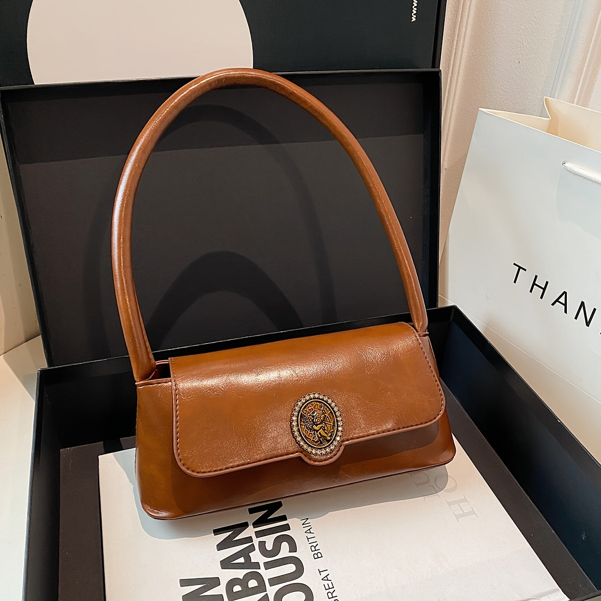 Ayollar uchun fransuz vintage uslubidagi yelka sumkasi, nafis jigarrang rangda, metall emblema, magnit yopish va polyester astar bilan. Har kuni foydalanish uchun ko'p funksiyali va zamonaviy.