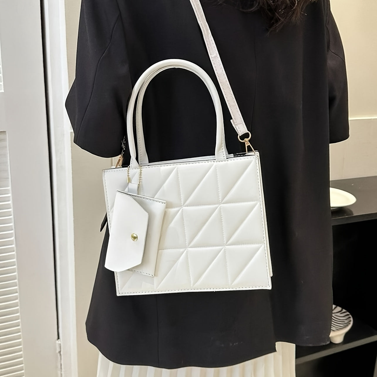 Qora qoplangan sintetik charm sumkasi, oltin detallari va ajraladigan uzun cho‘ntak bilan