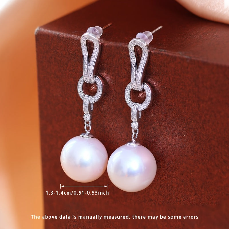 Kolleksiyangizga ushbu zarur Pearl Dangling Earrings bilan nafislik qo'shing. 13-14mm dumaloq tabiiy shirin suv marvaridlari bilan tayyorlangan, ushbu zamonaviy uzun sirg'alar S925 kumushdan yasalgan. Har bir juftlik noyob bo'lib, turli shakl va ...