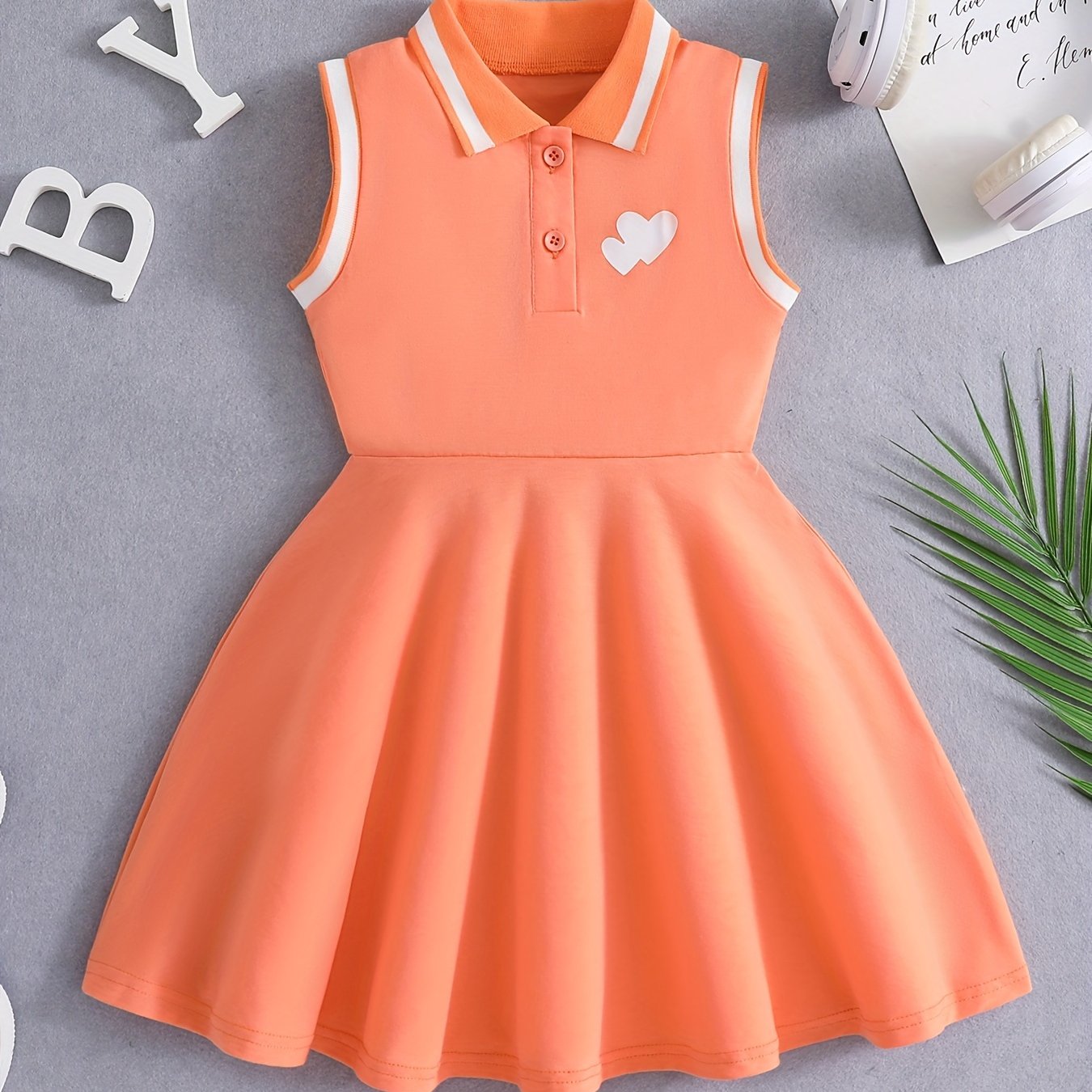 Qizlar uchun qizil tennis va sport libosi, nafas oladigan, teri so'radigan polyesterdan tayyorlangan, cho'ziluvchan va yengsiz dizayni bilan sport va tasodifiy kiyimlar uchun qora yozuvlar bilan sportiy nafislikni taqdim etadi.