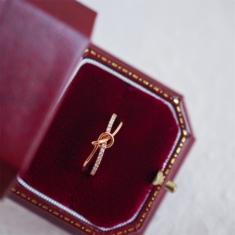 Ushbu ajoyib uzuk zamonaviy tugun dizayniga ega bo'lib, 925 sterling kumushdan tayyorlangan va porloq kubik zirkoniy aksentlari bilan bezatilgan. Bu sizning hayotingizdagi har qanday maxsus ayol uchun mukammal sovg'a.