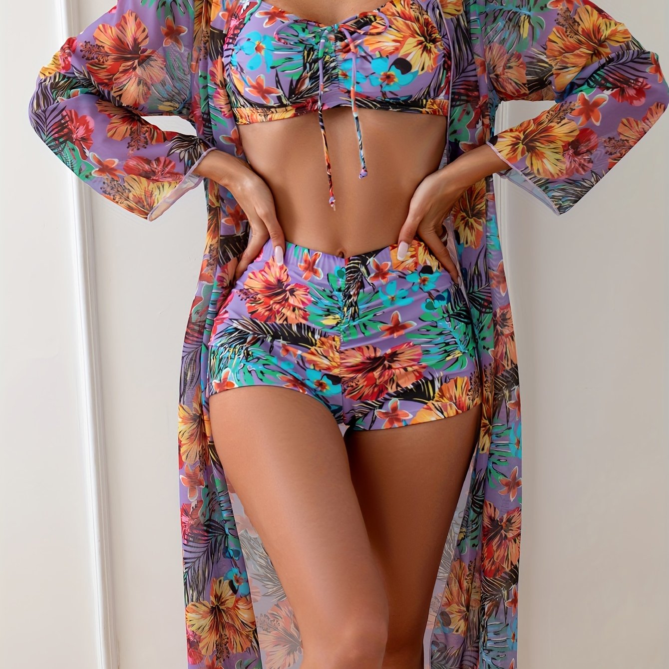 Uch qismli tropik gullar printi bilan bikini to'plami, yopishqoq, tortishqoq old qismi bo'lgan crop top va yuqori bel boxershorts - yozgi plyaj kiyimlari uchun mukammal.