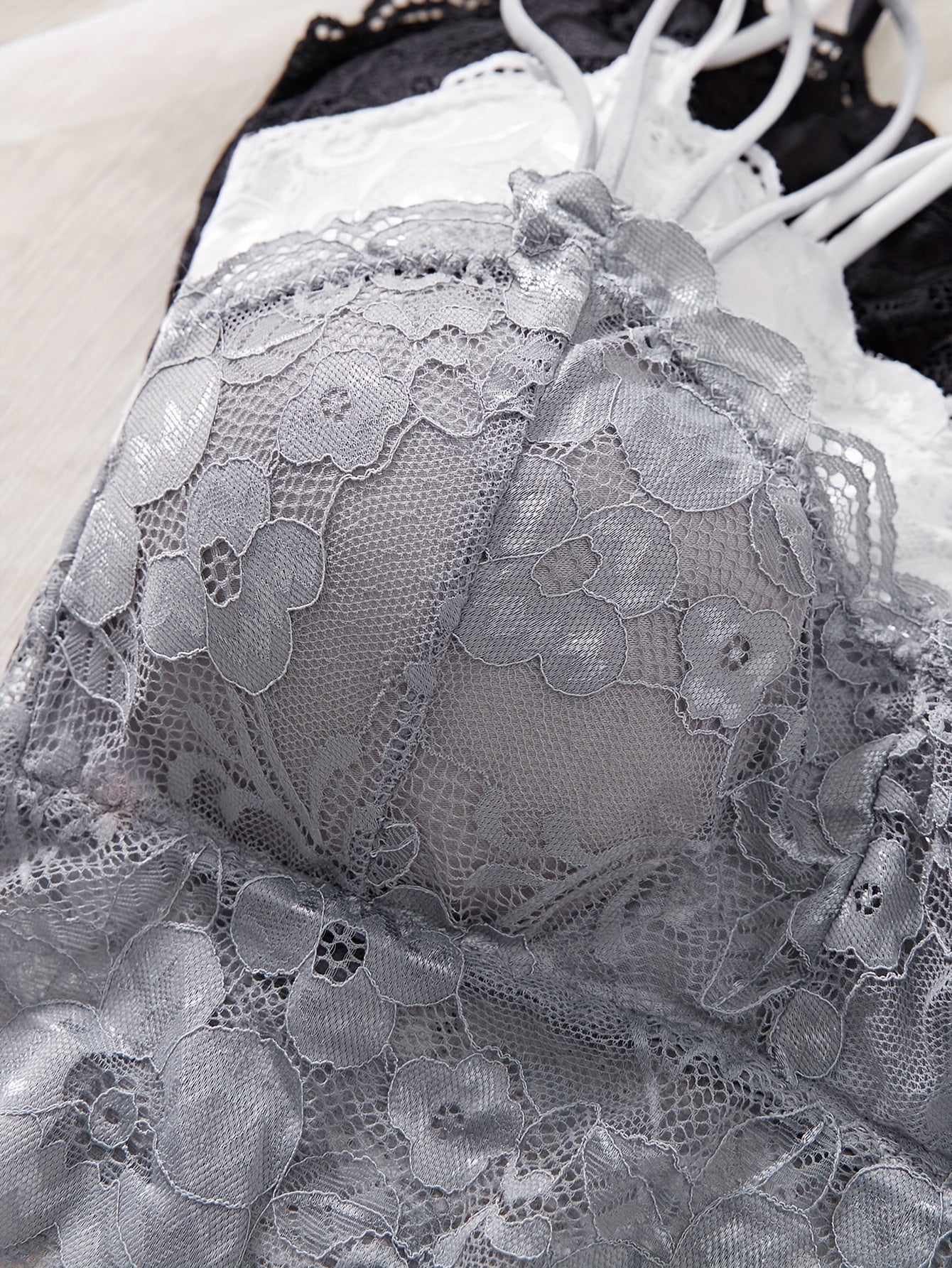 Fransuz dantelli bralette to'plami, olib tashlanadigan yostiqlar bilan, past qo'llab-quvvatlash, uchburchak thong, dantel tafsiloti, qora, oq yoki kulrang rangda. Kattalar uchun poliamiddan tayyorlangan.