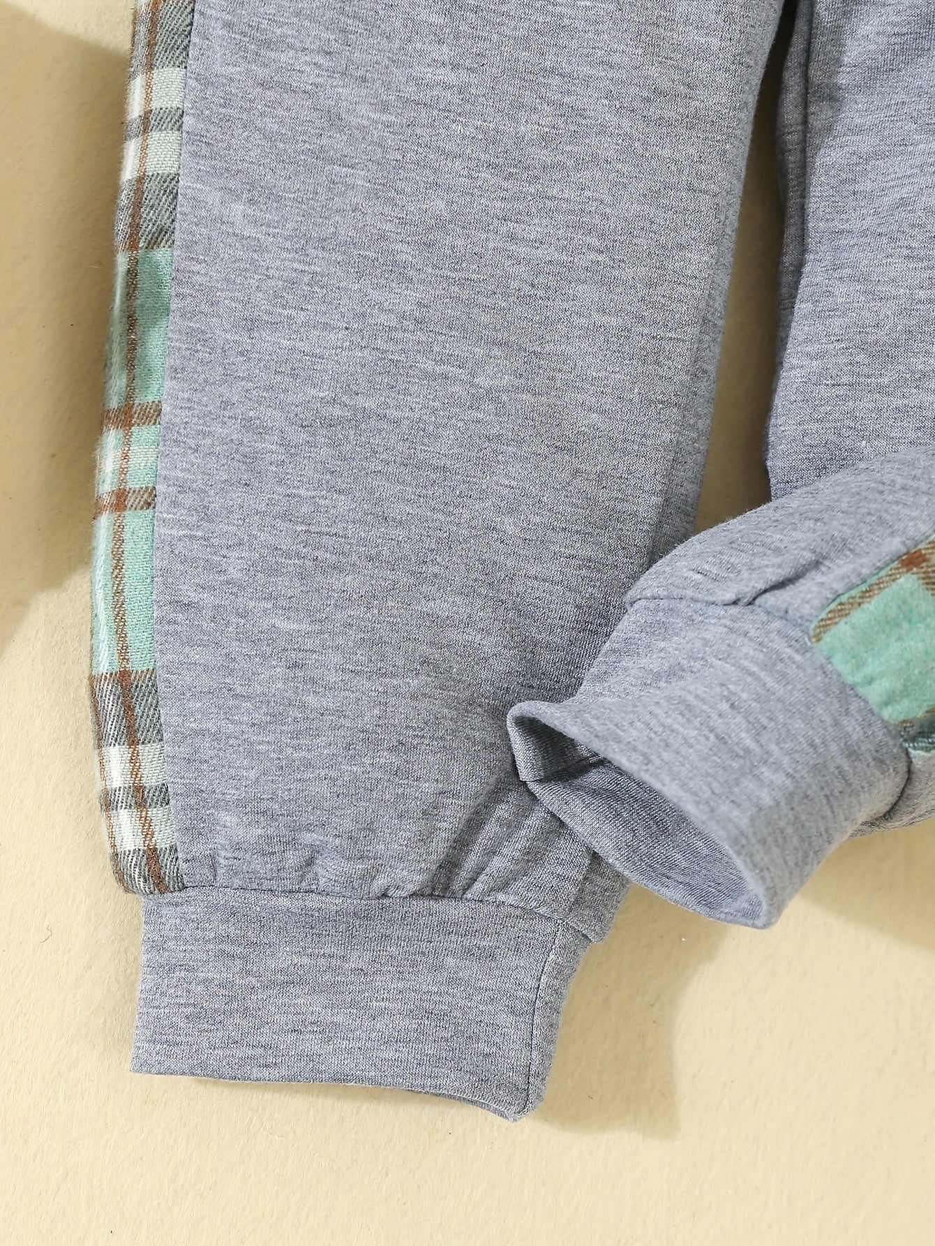 Yigitlar uchun kundalik to'plamda tekislikli kapüşonli asosiy kiyim va rangli blokli shimlar mavjud, bahor va kuz uchun