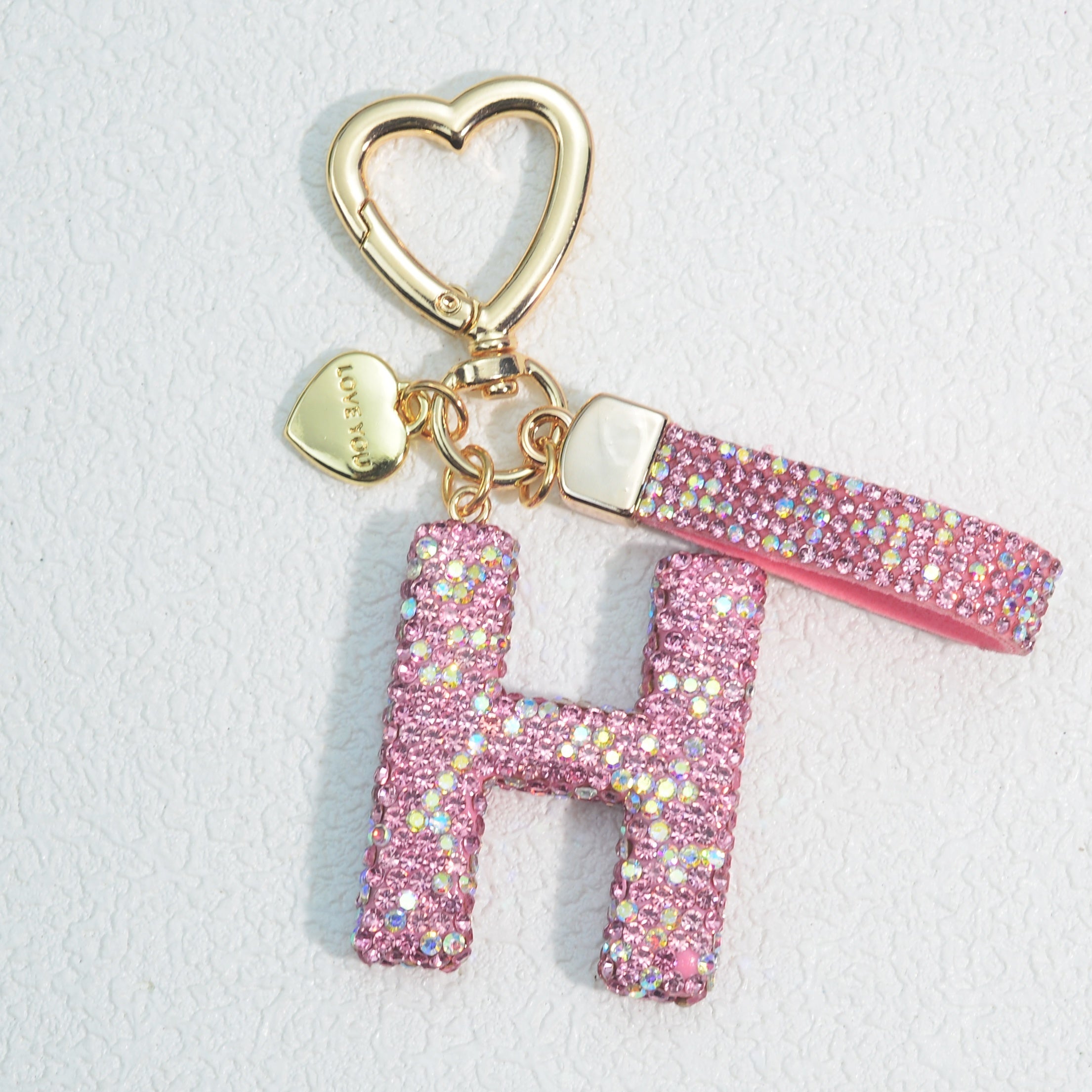 Llavero de PVC con iniciales de pedrería rosa y blanca con cierre de puño para mujeres