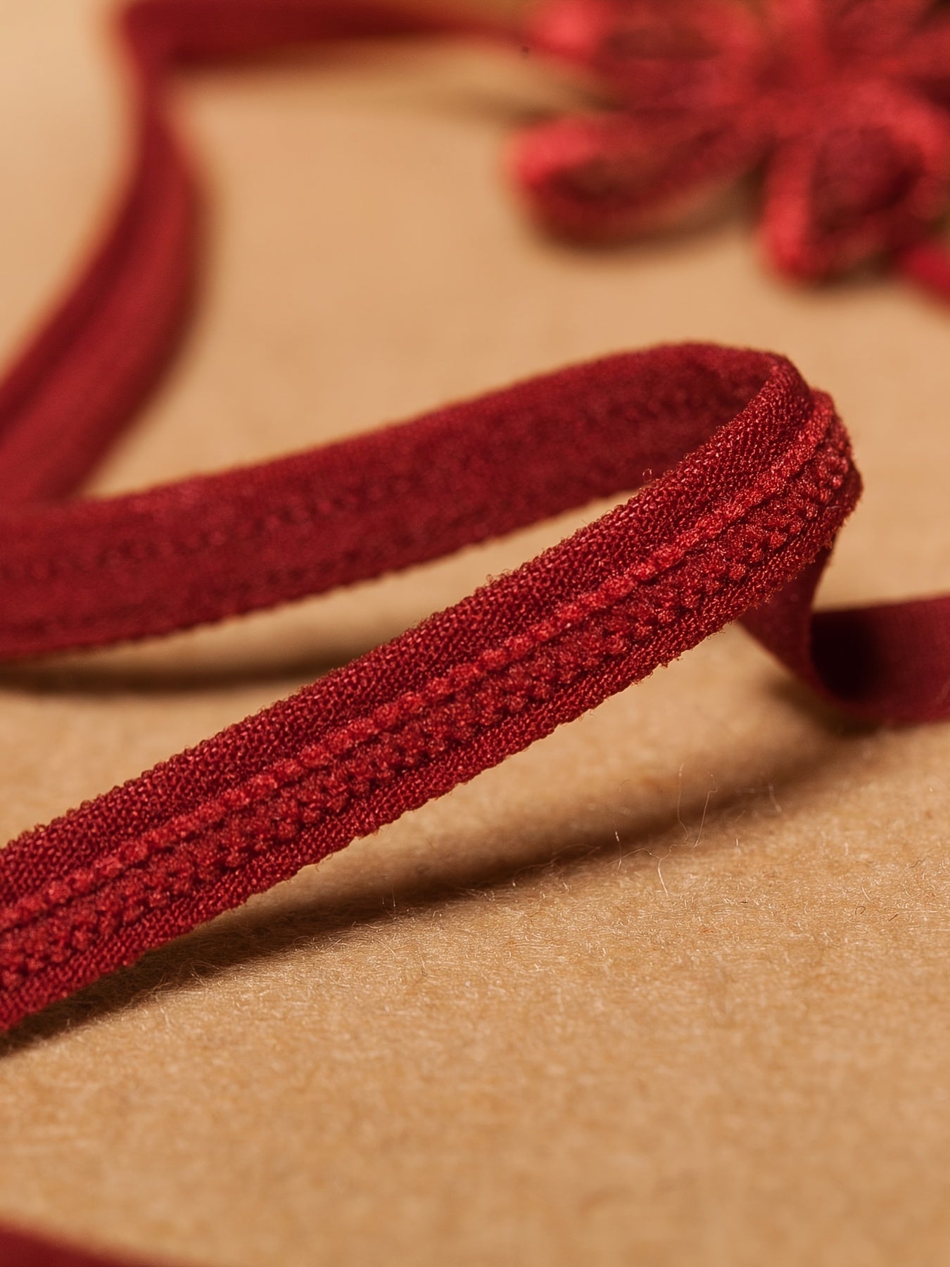 Красный кружевной корсет с перловыми деталями и соответствующим низким стрингом, украшенным цветами крючком и бисерными элементами.