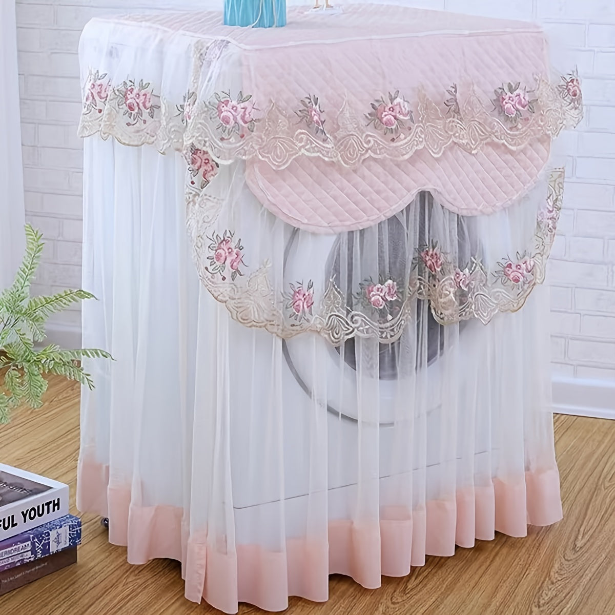 Gul naqshli va qirrali trim bilan bezatilgan pushti va oq dantel kir yuvish mashinasi qopqog'i, yon tomondan ochiladigan modellarga mos kelish, chang va quyoshdan himoya qilishni ta'minlaydi. Polyester matodan tayyorlangan.