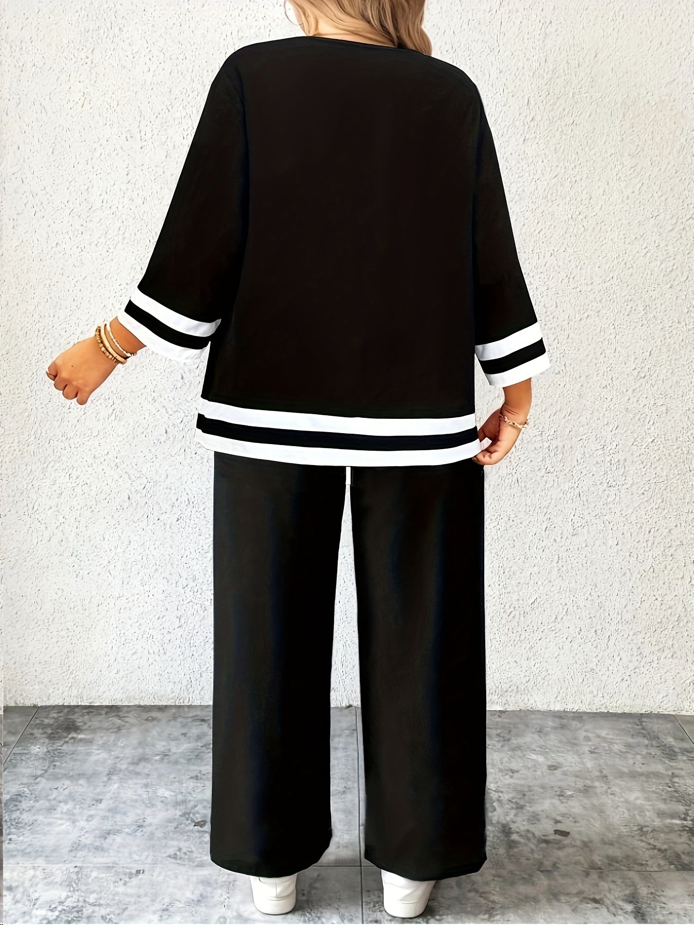 Ayollar uchun zamonaviy katta o'lchamdagi kostyum, to'r tafsilotlari va chiziqli mansetlari bilan crew neck yuqori qismi, to'g'ri kesim va o'rtacha cho'zilish bilan birga mustahkam rangli shimlar bilan to'ldirilgan.