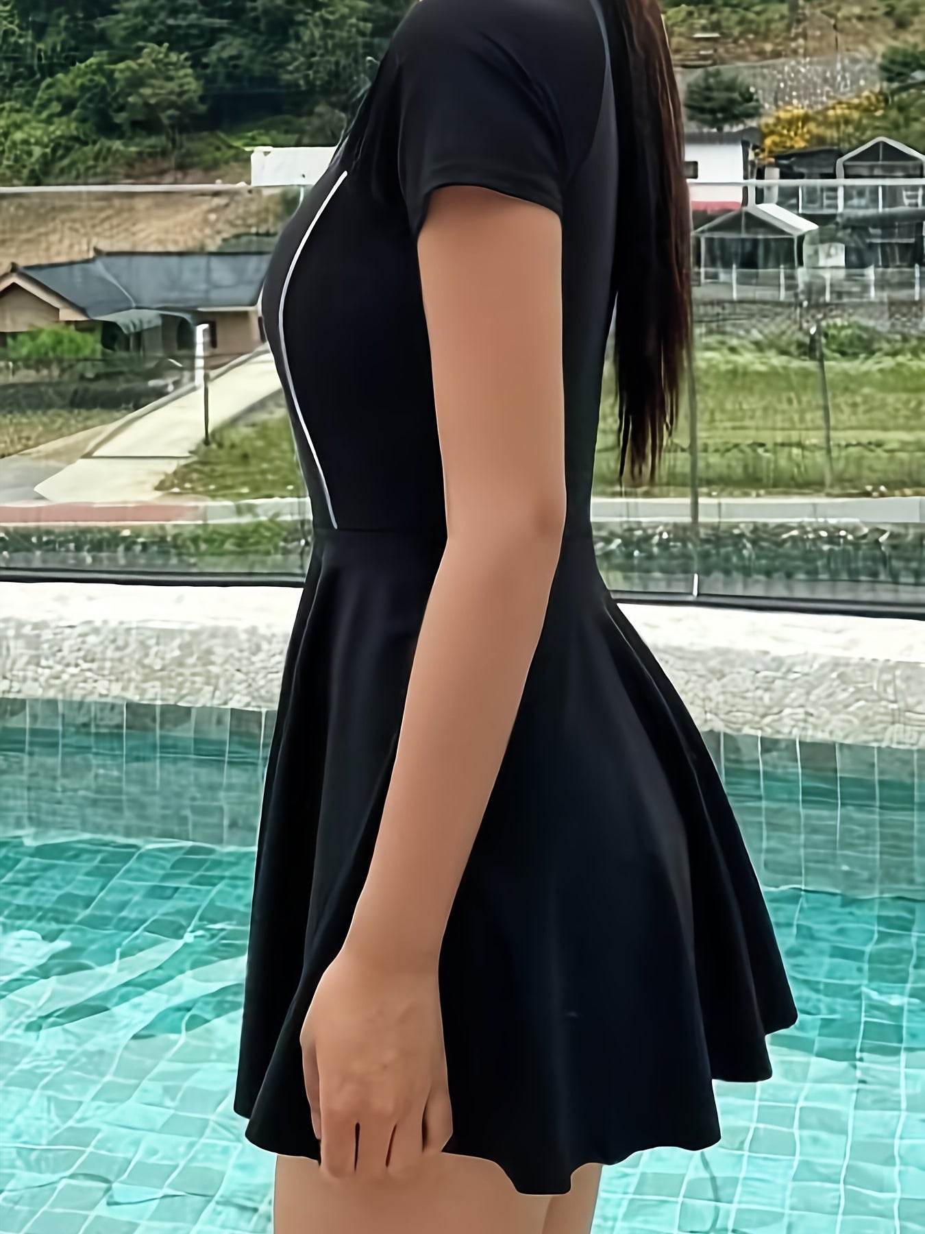 Ayollar uchun sport uslubidagi qora bir parcha suzish kiyimi, zip detali bilan, yuqori elastik nylon/elastan aralashmasidan tayyorlangan. Qisqa yenglar, dumaloq bo'yin va shaffof bo'lmagan mato bilan jihozlangan.