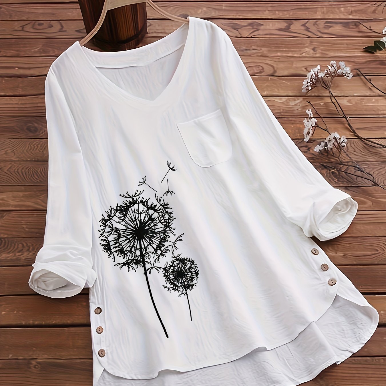 Tengiz ko'k dandelion print bluzka, V-shakl, uzun yenglar, qirrali pastki qismi va tugma aksentlari bilan. Polyester aralashmasidan tayyorlangan va mashinada yuvish uchun mos. Katta o'lchamdagi ayollar uchun ideal.