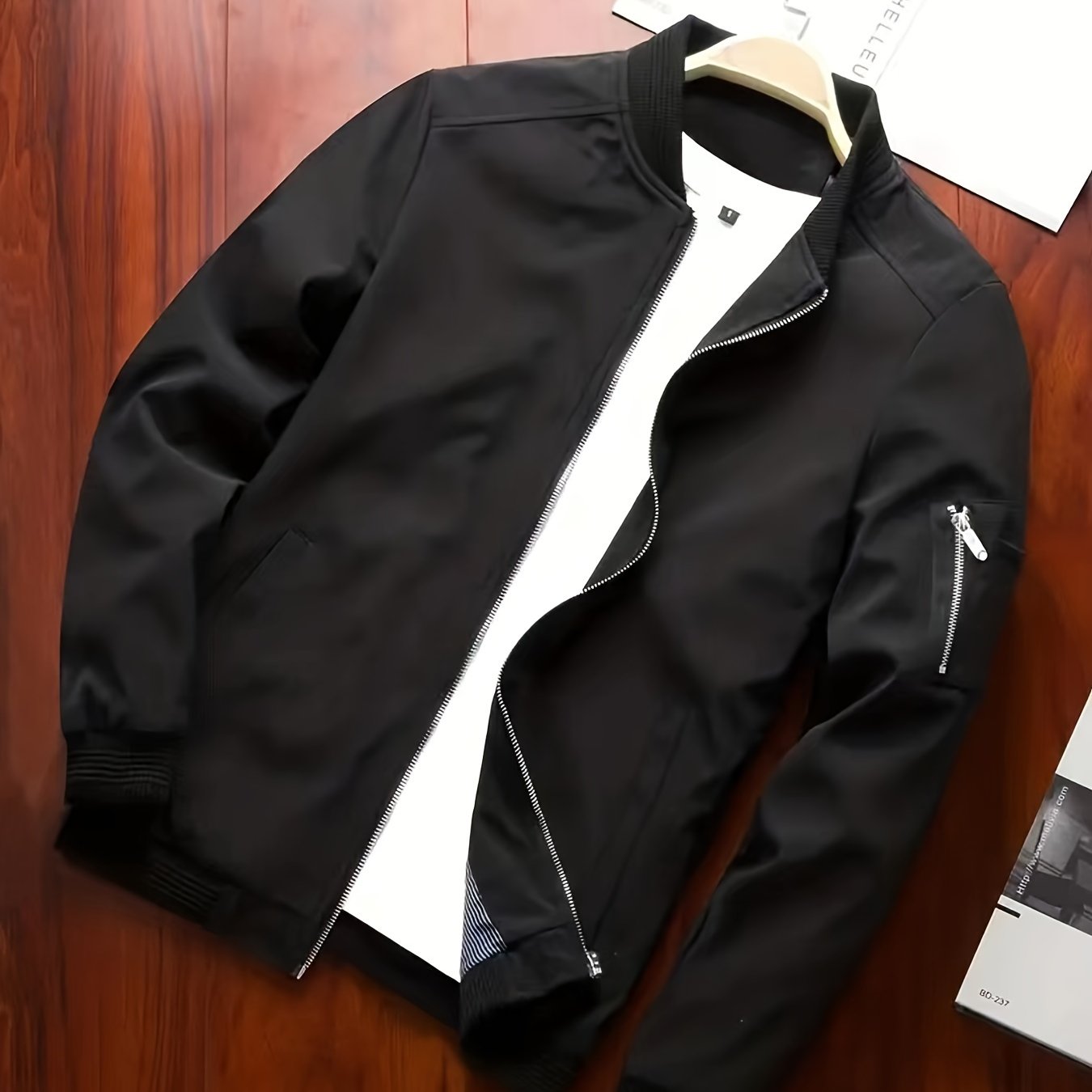 Erkaklar uchun polyester sport jakketi, mandarin yelka va zip yopilishi bilan. Bir rangli, cho'zilmaydigan mato, oddiy kesim. Yugurish va piyoda yurish kabi norasmiy ochiq havoda faoliyatlar uchun mos. 100%