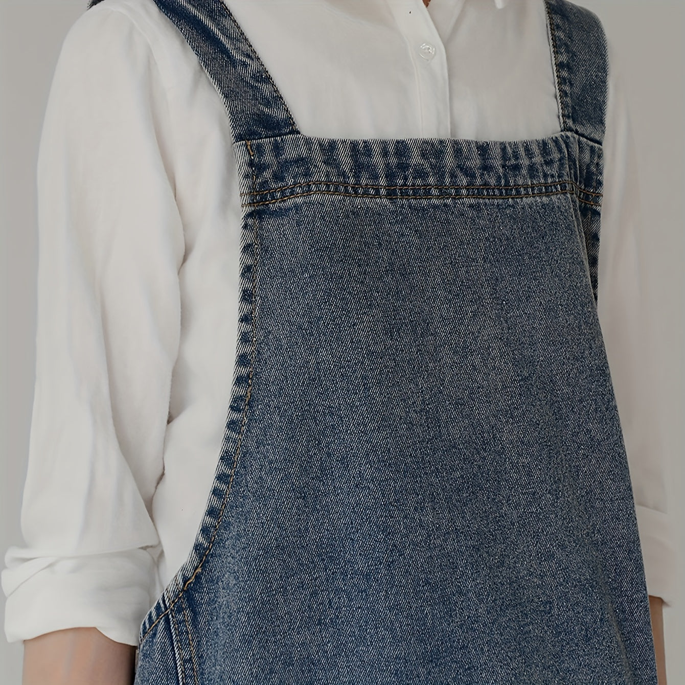 Vintage uslubidagi denim apron, cho'ntaklar bilan, sozlanadigan tasmalari va oshxona va restoran ishlarida foydalanish uchun suv o'tkazmaydigan dizayn.