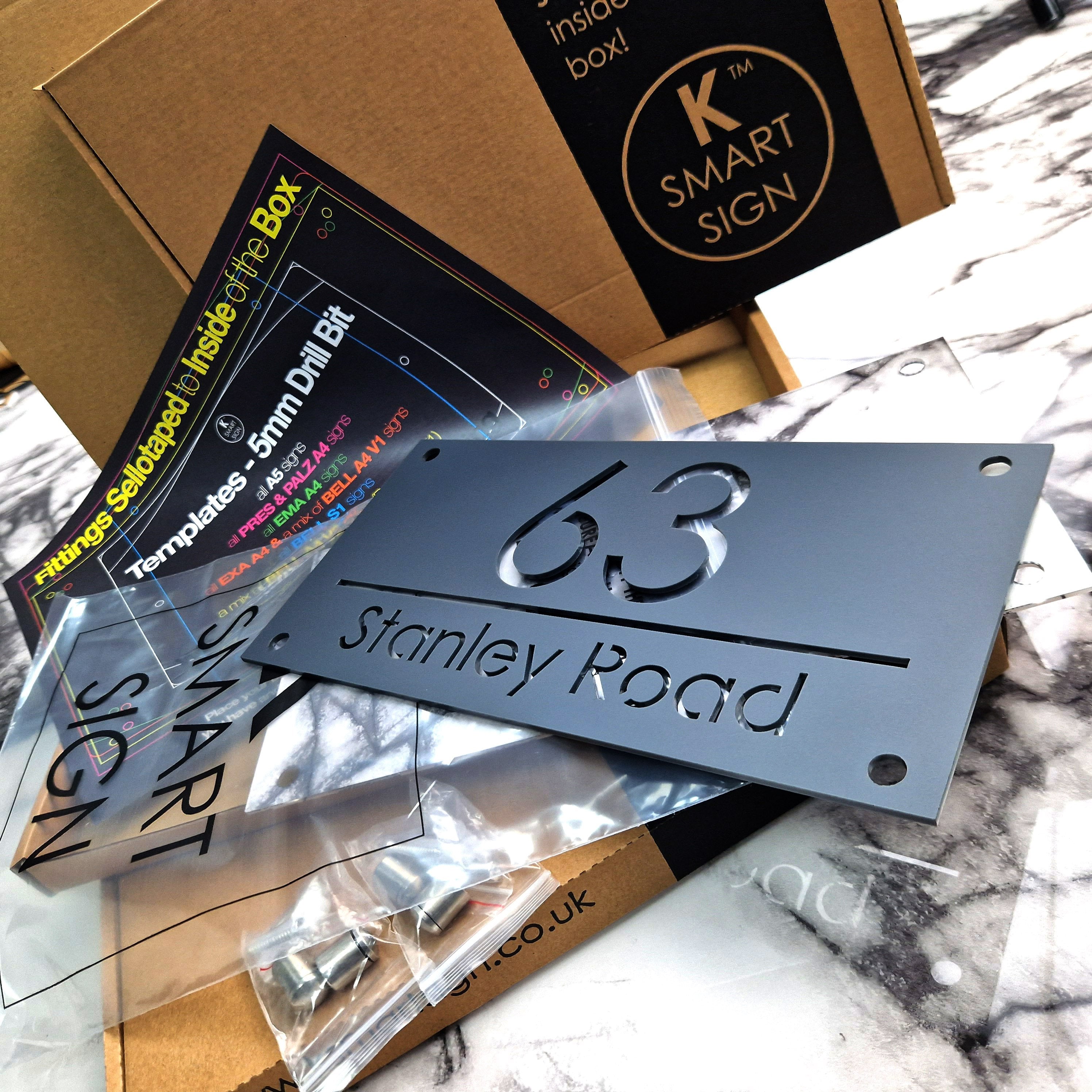 Matte kulrang va kumush oynali qoplamaga ega lazer kesilgan akrildan tayyorlangan maxsus Britaniya uy raqami belgilari.