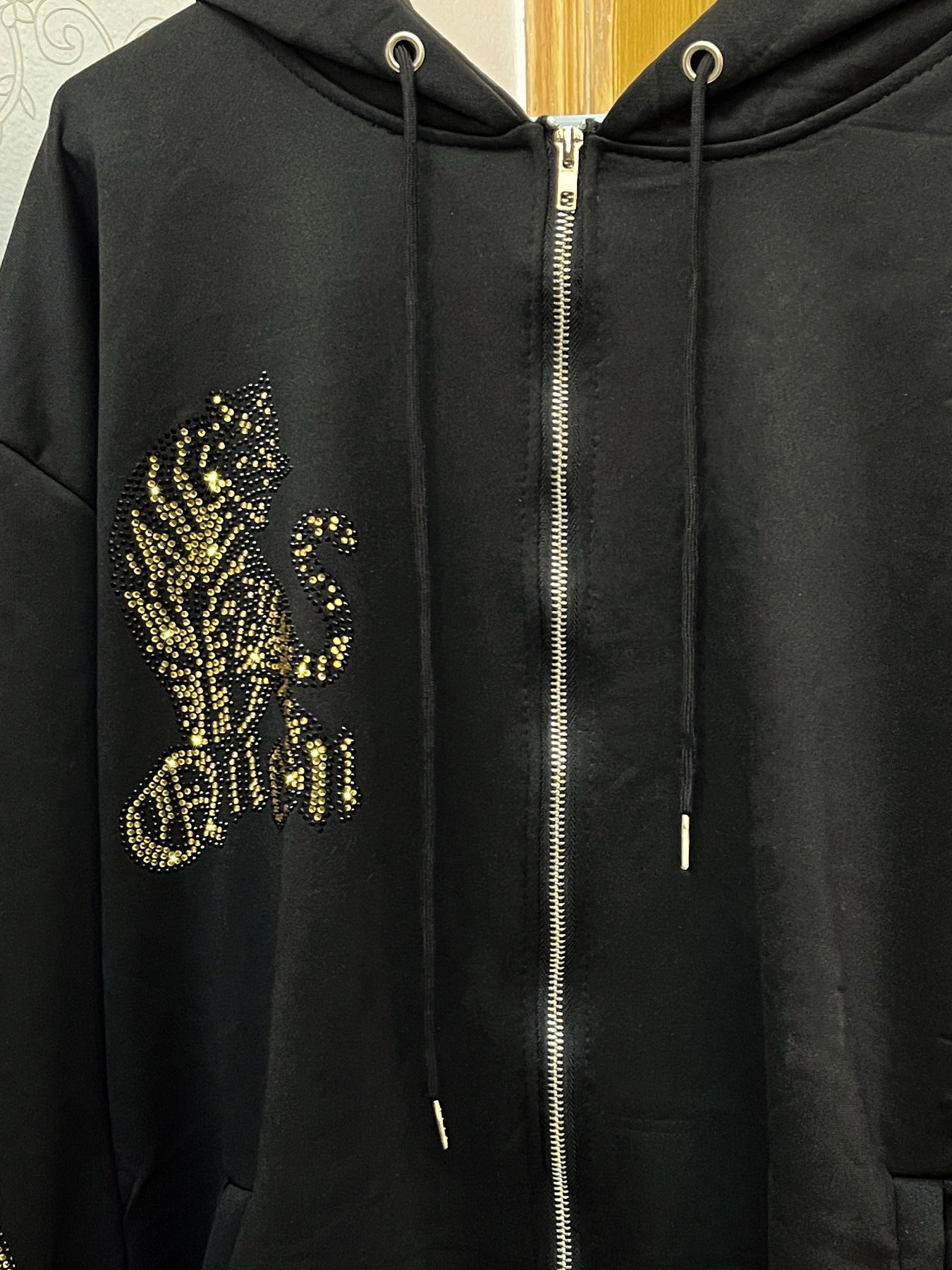 Katta o'lchamdagi ayollar uchun kapüşonli ko'ylak, porlaydigan yo'lbars rhinestones bilan, 100% polyester to'qima matodan tayyorlangan. U uzun yenglar, kapüşon, geometrik naqsh, keng cho'ntak bilan jihozlangan, bahor/kovak uchun mos.