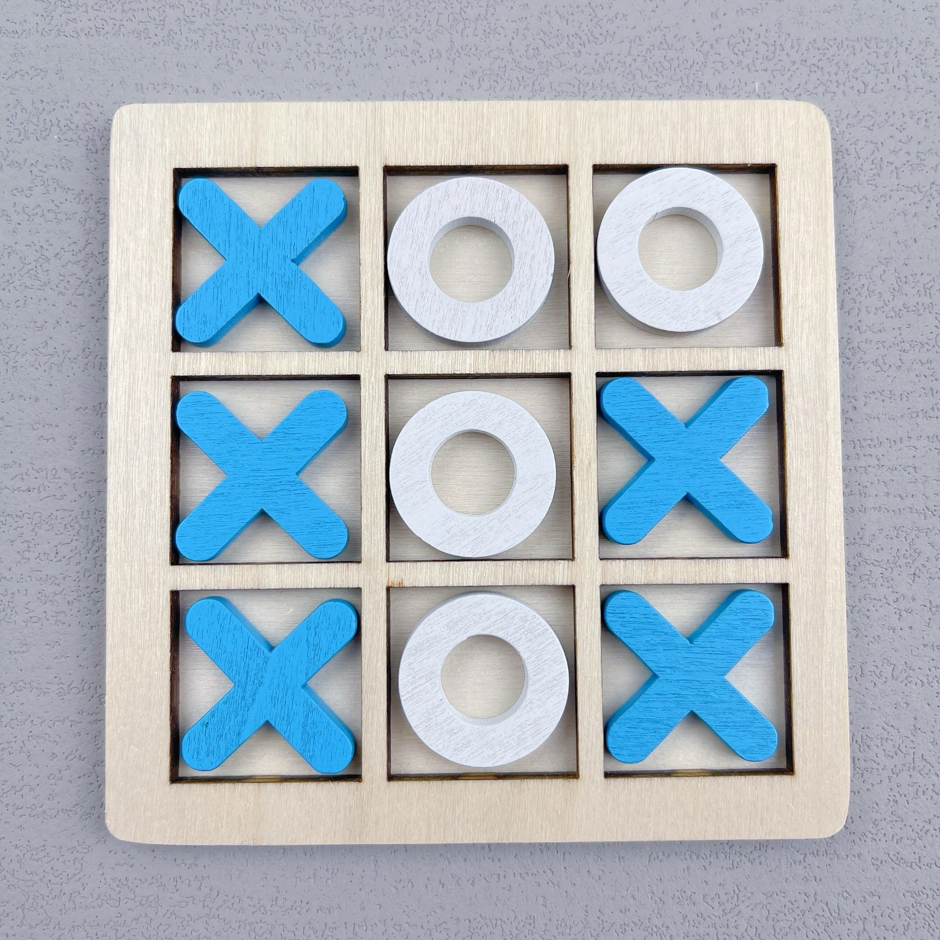 Ta'lim beruvchi, ikki o'yinchi uchun Tic Tac Toe o'yini, turli rangdagi yog'och XO qismlari bilan.