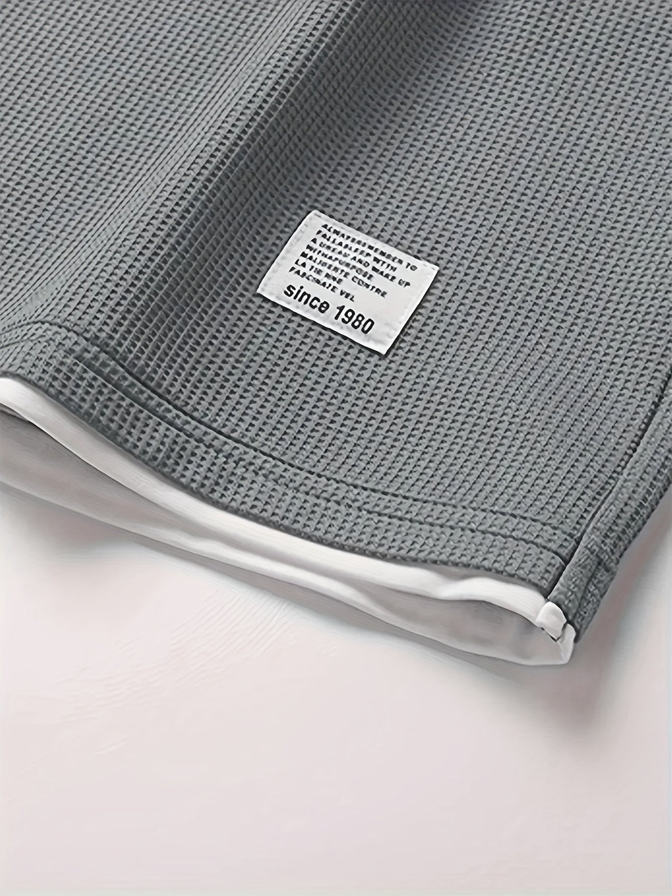 Erkaklar uchun tasodifiy vafli to'qilgan pijama to'plami, kulrang va qora rangda, qisqa yengli yuqori va elastik belga ega shortlar. Quyi qismida aplikatsiya bezaklari va qulaylik uchun yumshoq polyester mato mavjud.