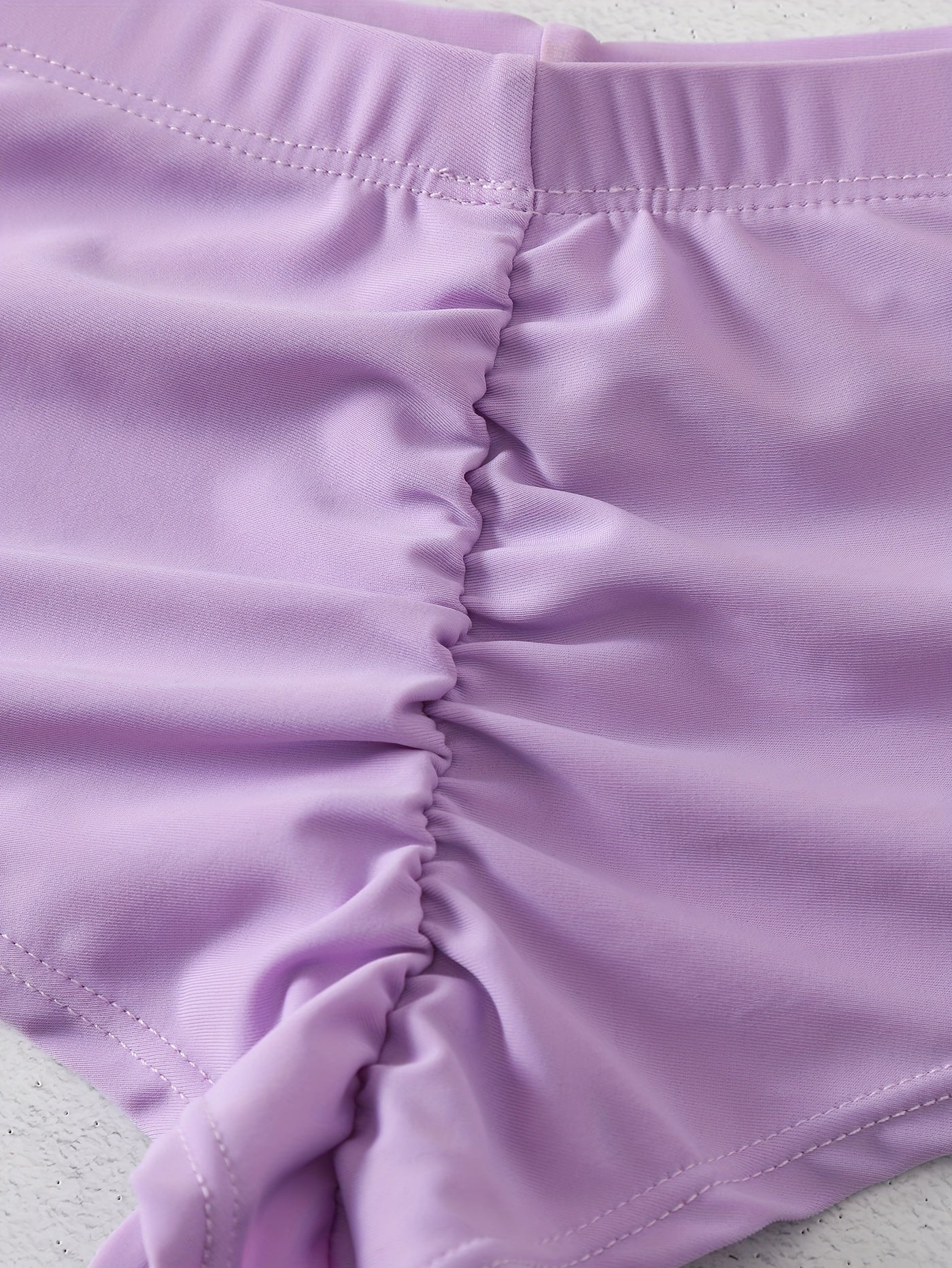 Yumshoq rangli yuqori cho'ziluvchan bikini pastki qismi, to'plangan, jozibali yuqori kesim uslubi.