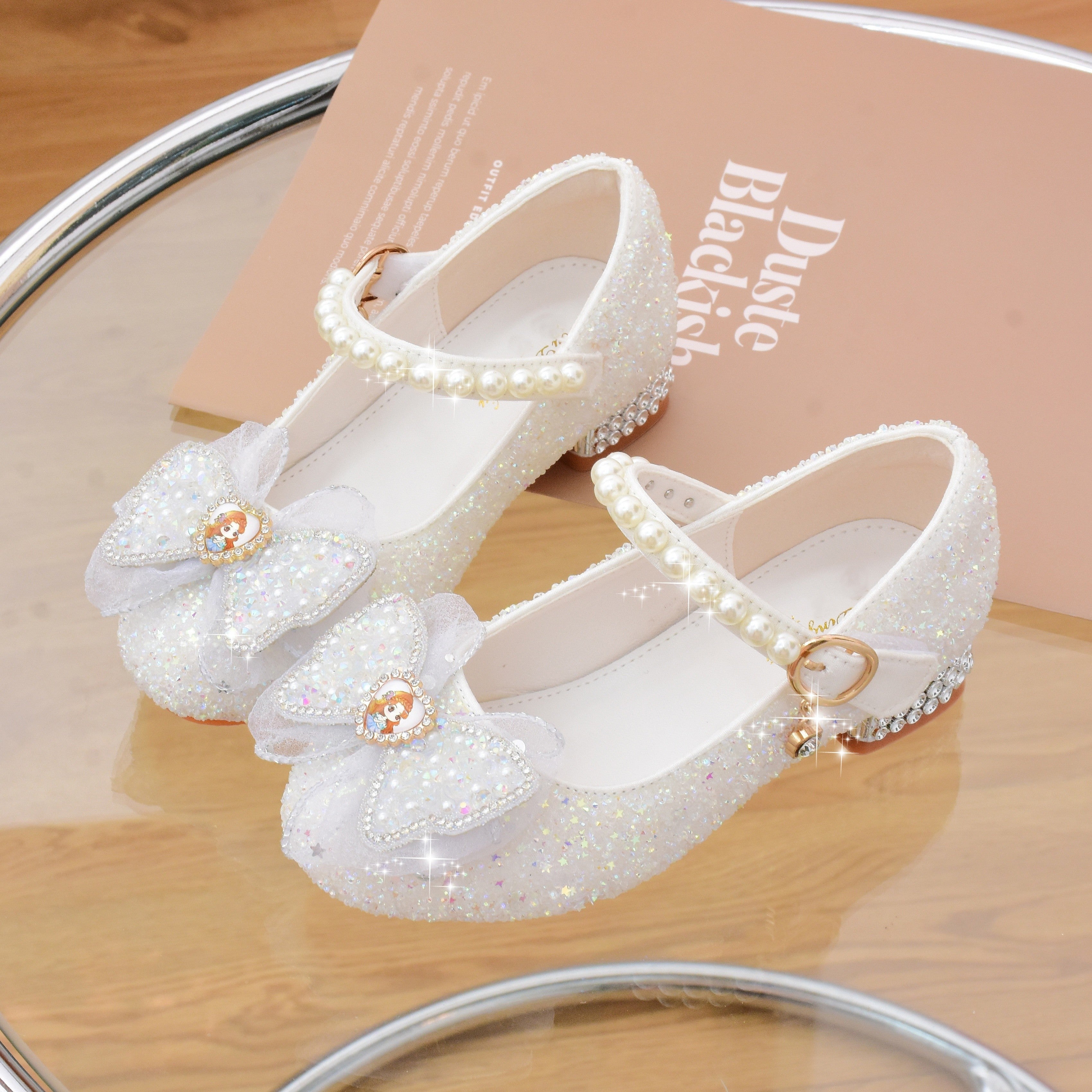 Pushti porloq kapalak kamonli Mary Jane tekis poyabzal, marvarid aksentlari bilan, to'ylar, partiyalar va rasmiy tadbirlar uchun mukammal.