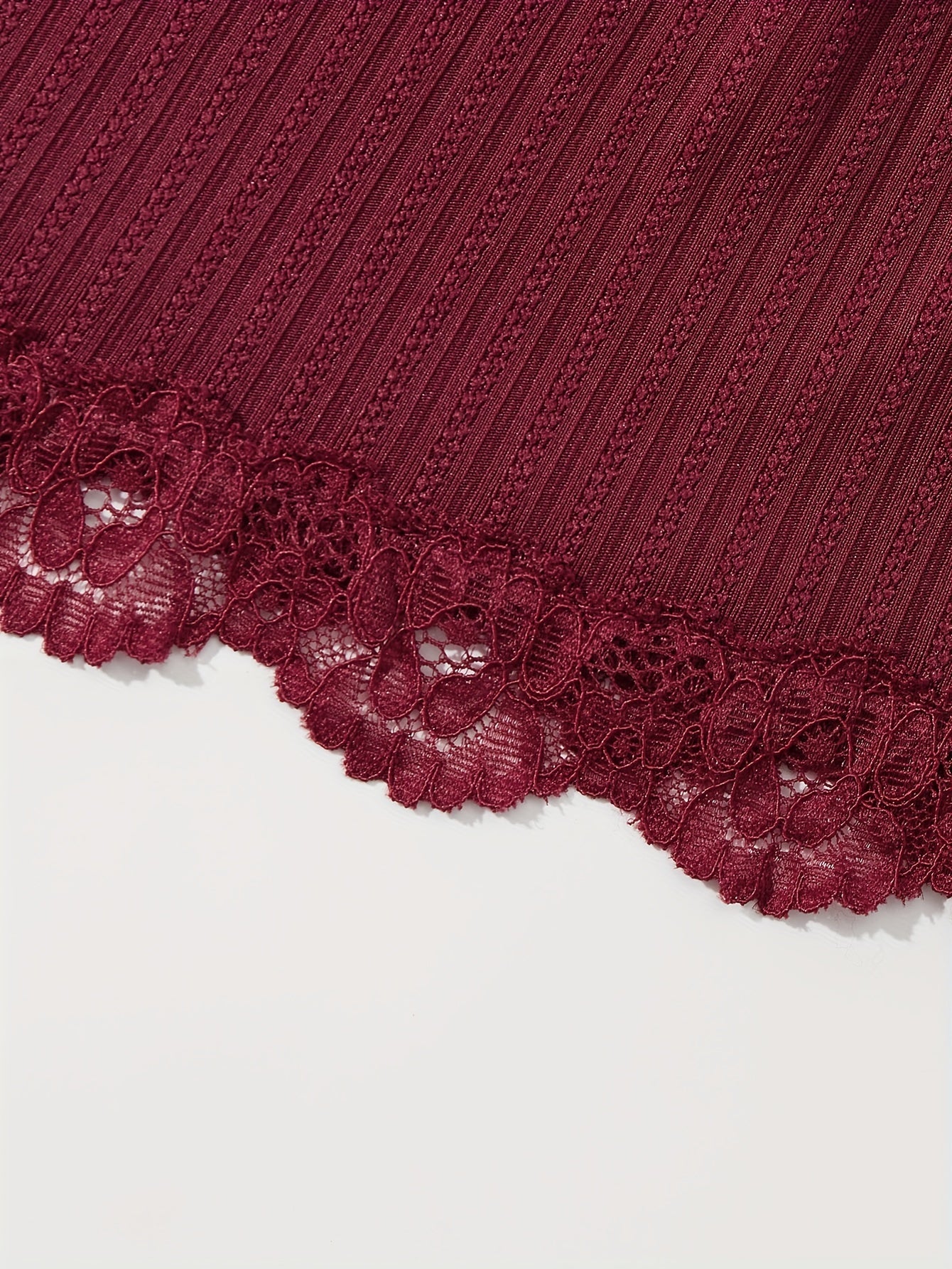 3-qismli dantel tikuvli lounge to'plami V-shaklidagi kamzuli bluzka va elastik belli shortlardan iborat bo'lib, ayollarning uyda kiyish va uxlash kiyimlari uchun mo'ljallangan.