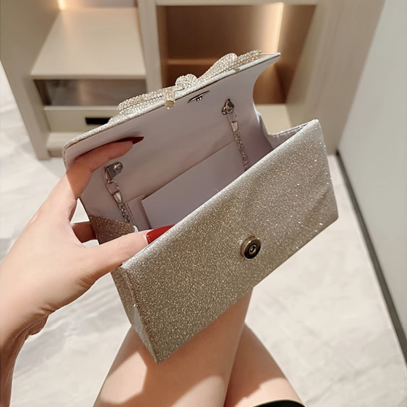 Стильная клатч-сумка для женщин с брошью в виде банта из страз и цепочным ремешком, выполненная из полиэстера. Магнитная застежка, доступна в черном, золотом и серебристо-сером цветах.