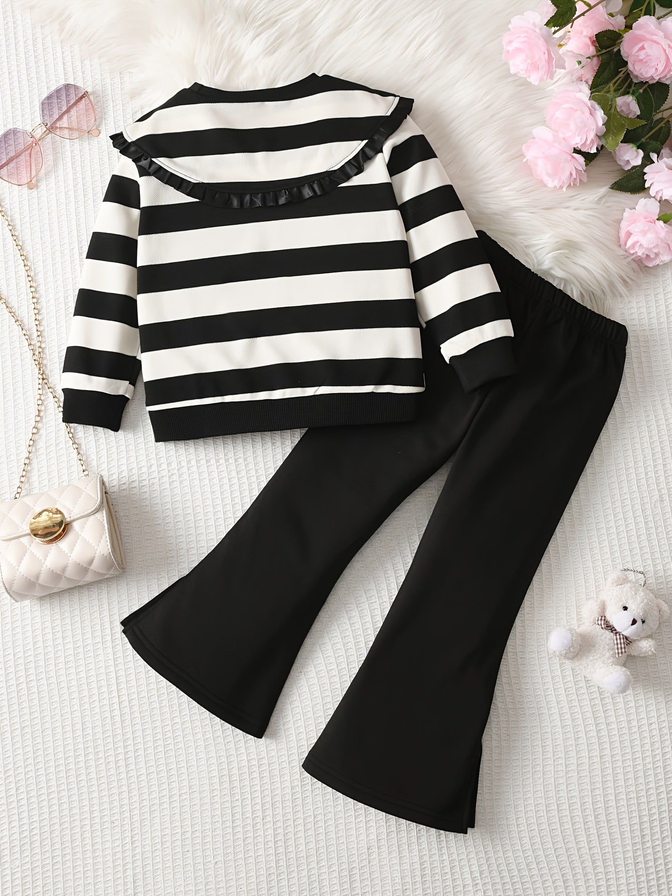 Kichkina qizning yengil qo'ltiq va chiziqli uzun yengli ko'ylagi, qora keng pastki shimlar bilan birga. Kuz va qish mavsumida kundalik qulaylik uchun ideal, ochiq havoda kiyish uchun mukammal.